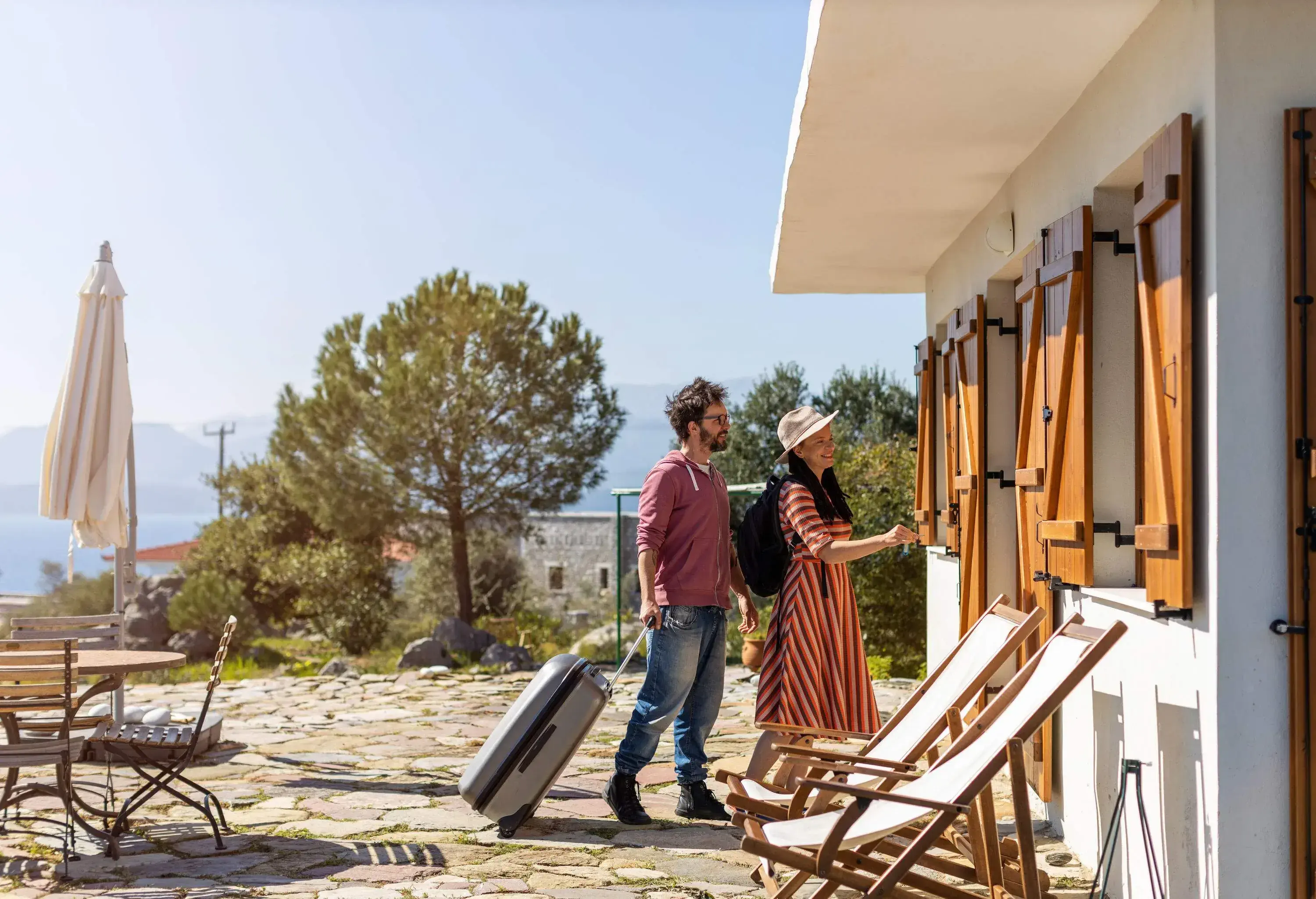 A couple arrives in a holiday home with their luggage.