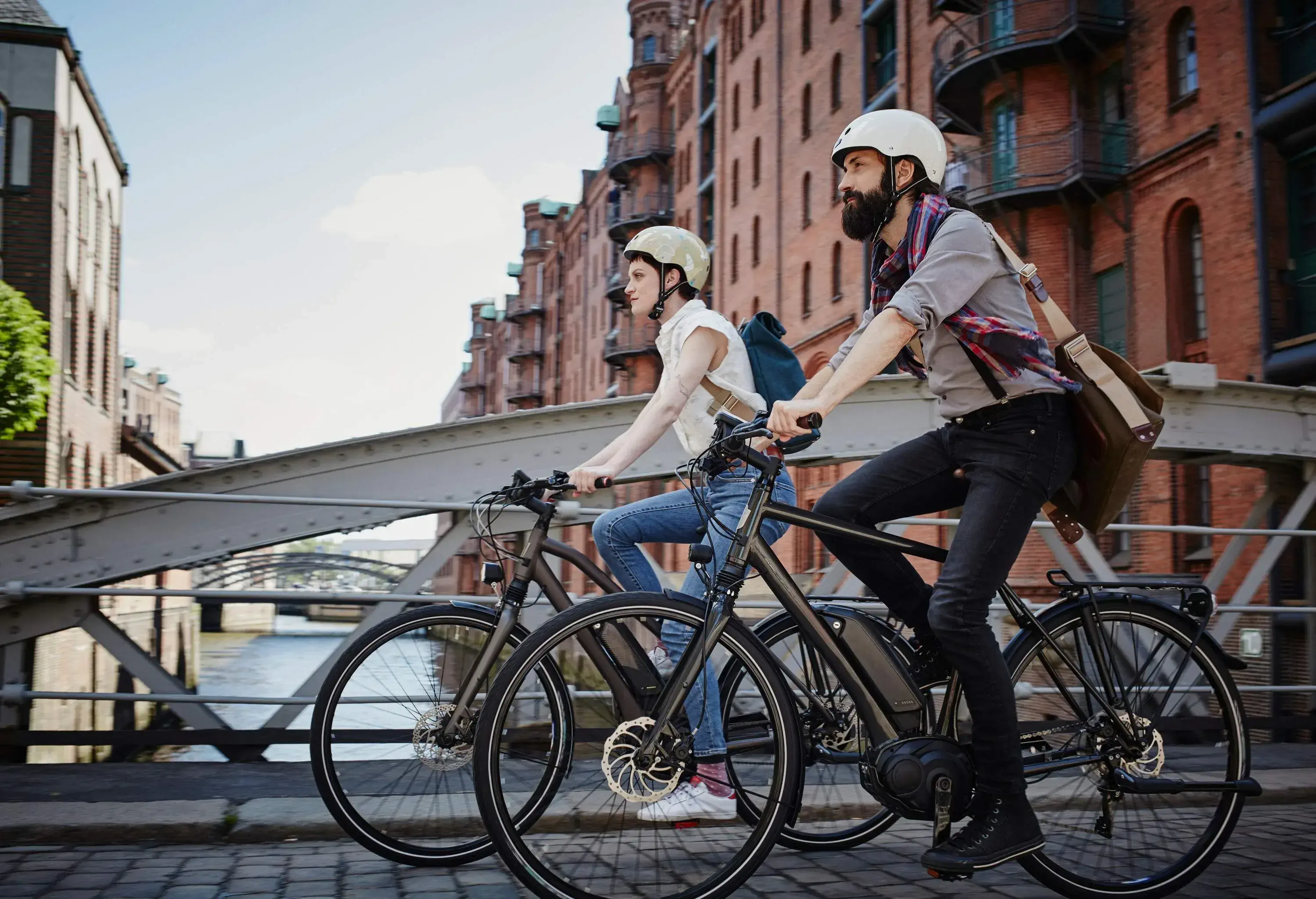 A man and a woman riding their bicycles across a bridge.