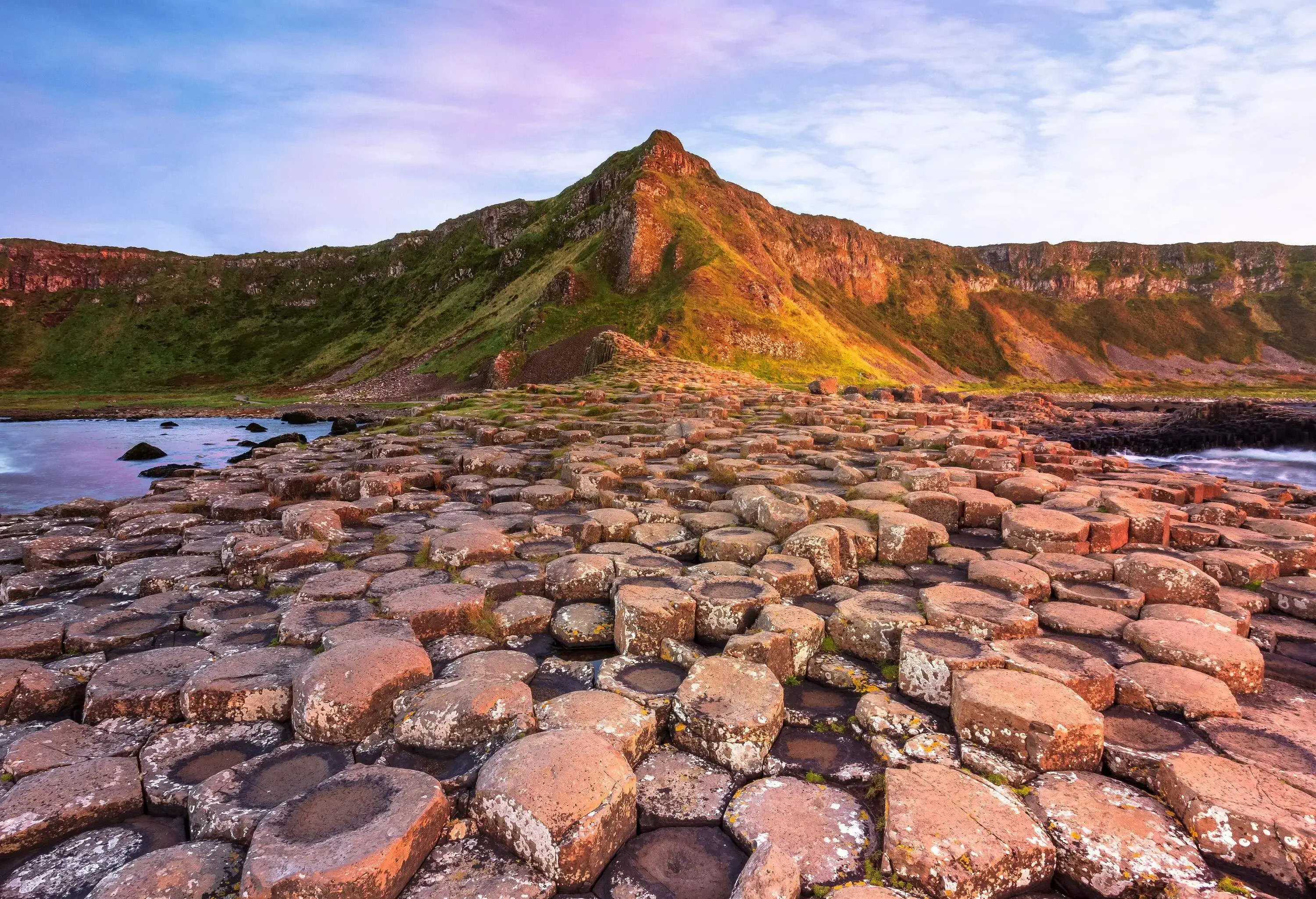 Impressive interlocking basalt columns of the Giant's Causeway on the coast surrounded by cliffs.