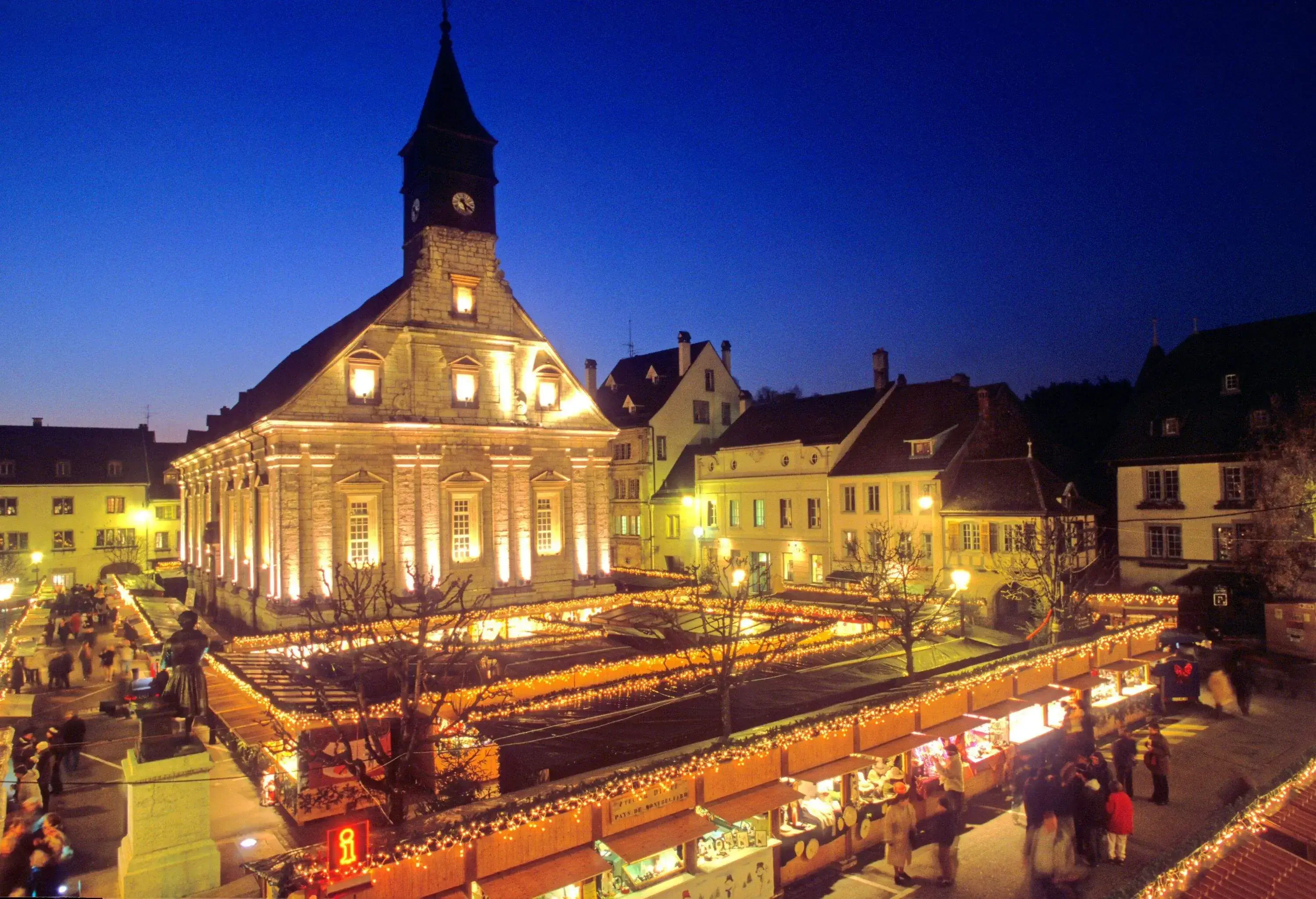 High angle view of festively illuminated cathedral in the main village square with Christmas market stands at night