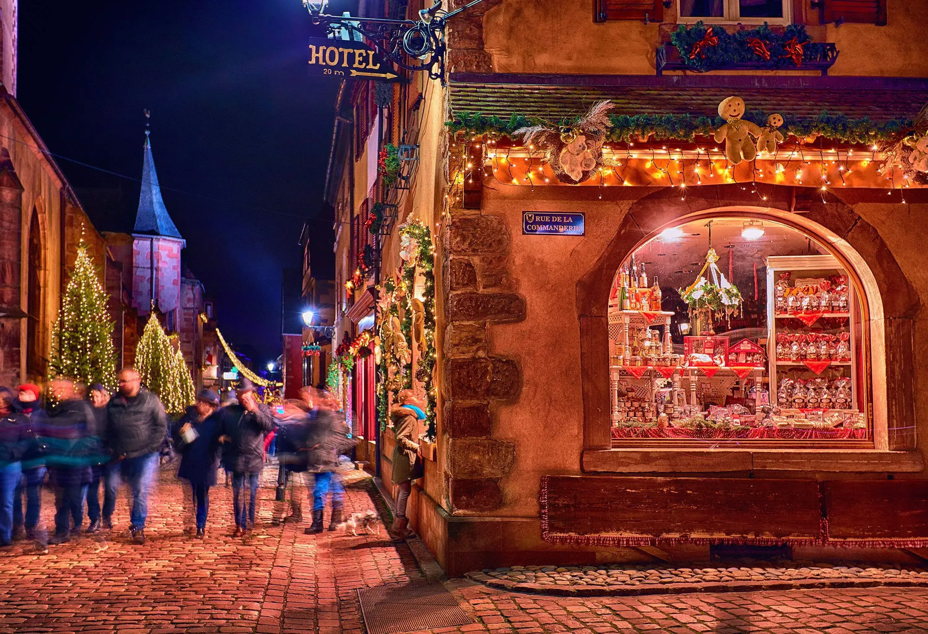 People flock to a cobbled street in the middle of shops and hotels on a Christmas holiday.
