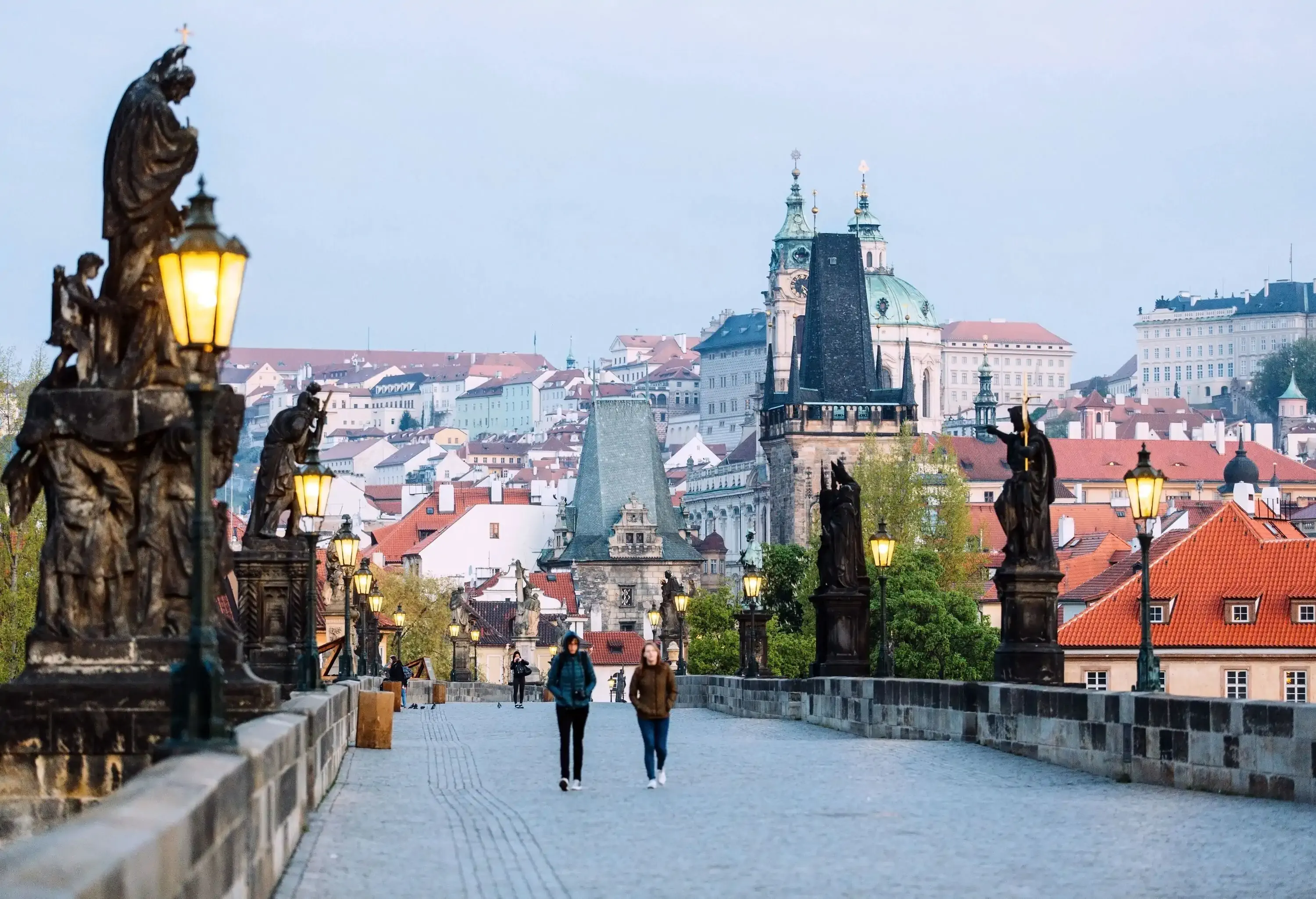 Two people walking on a stone bridge in old city centre of a European capital