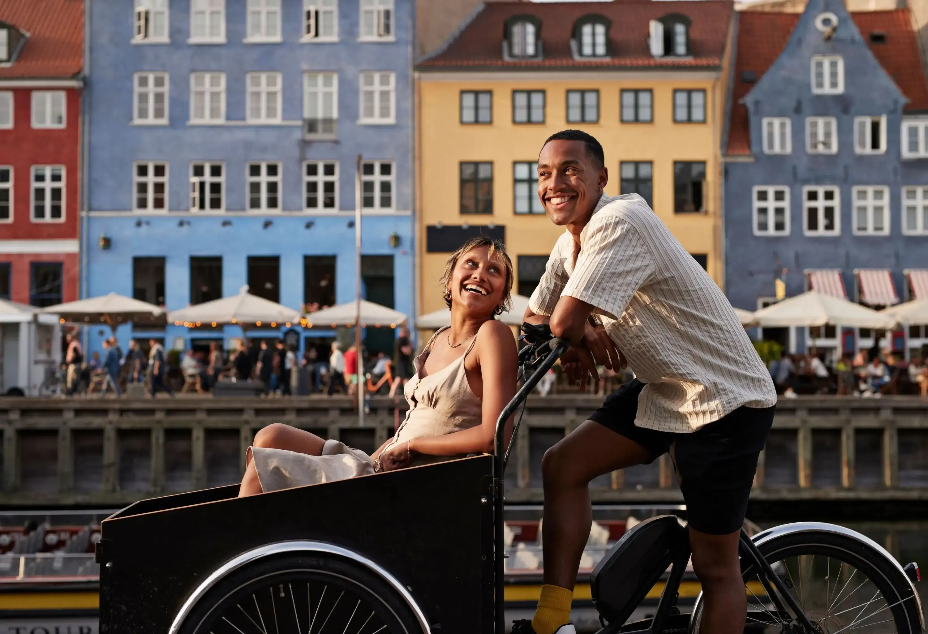 Happy young man with girlfriend in cargo bike at famous pier