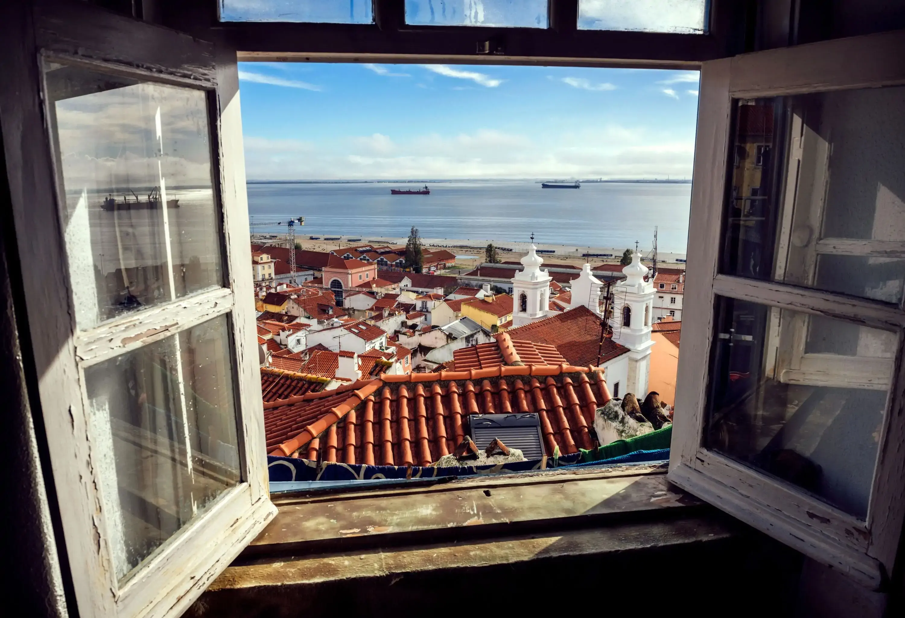 View from a window of old European city by the sea with boats in the background