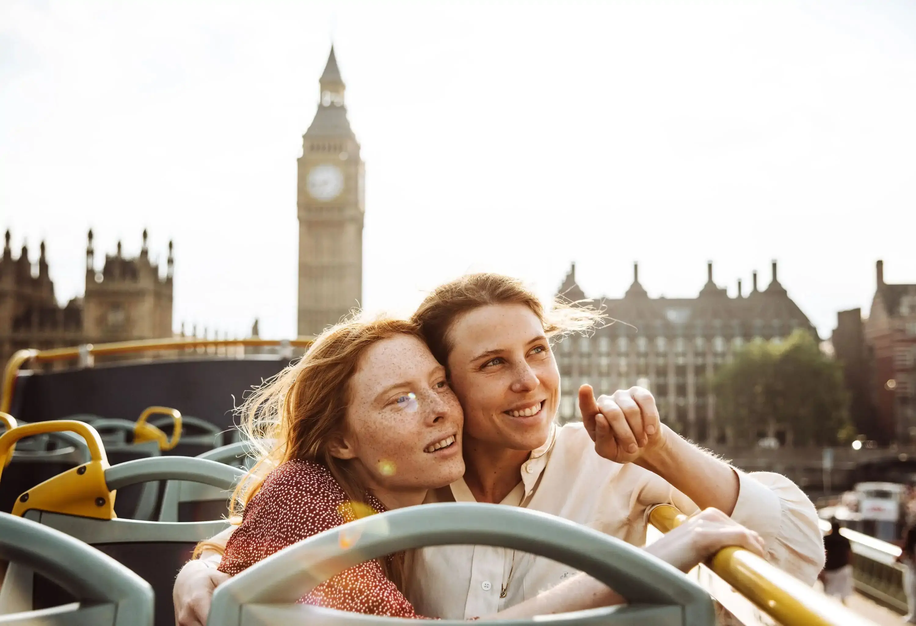 lesbian couple on an open top bus in London in front of famous landmark
