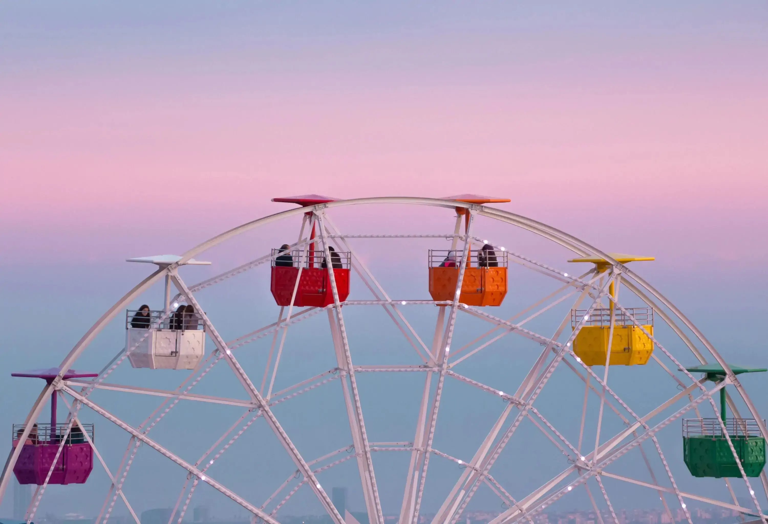 View of the colorful ferris wheel in the Tibidabo amusement park with families and couple spending the week end on the attractions.