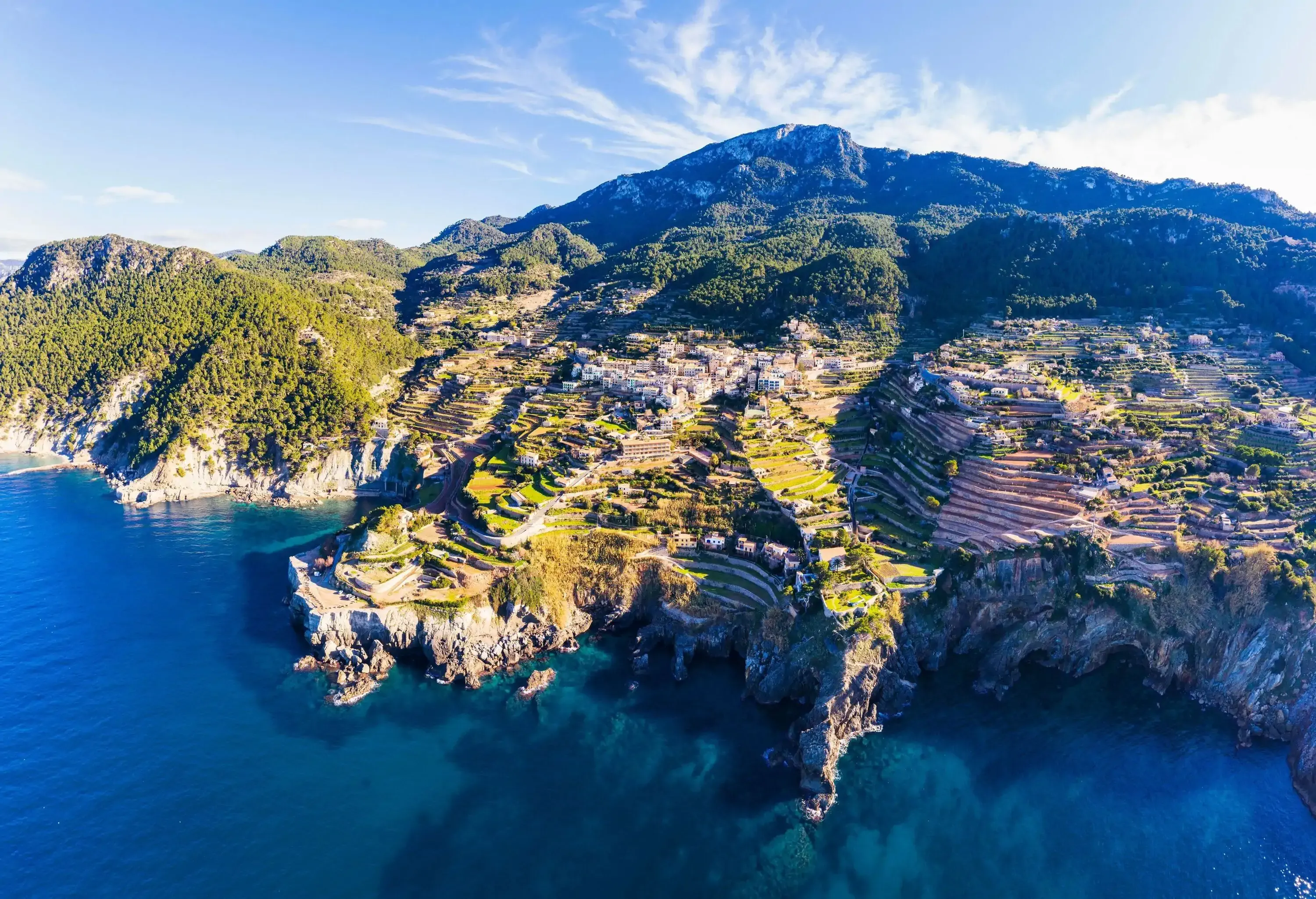 A coastal village with homes perched on terraced hills along steep cliffs with vast bay views.
