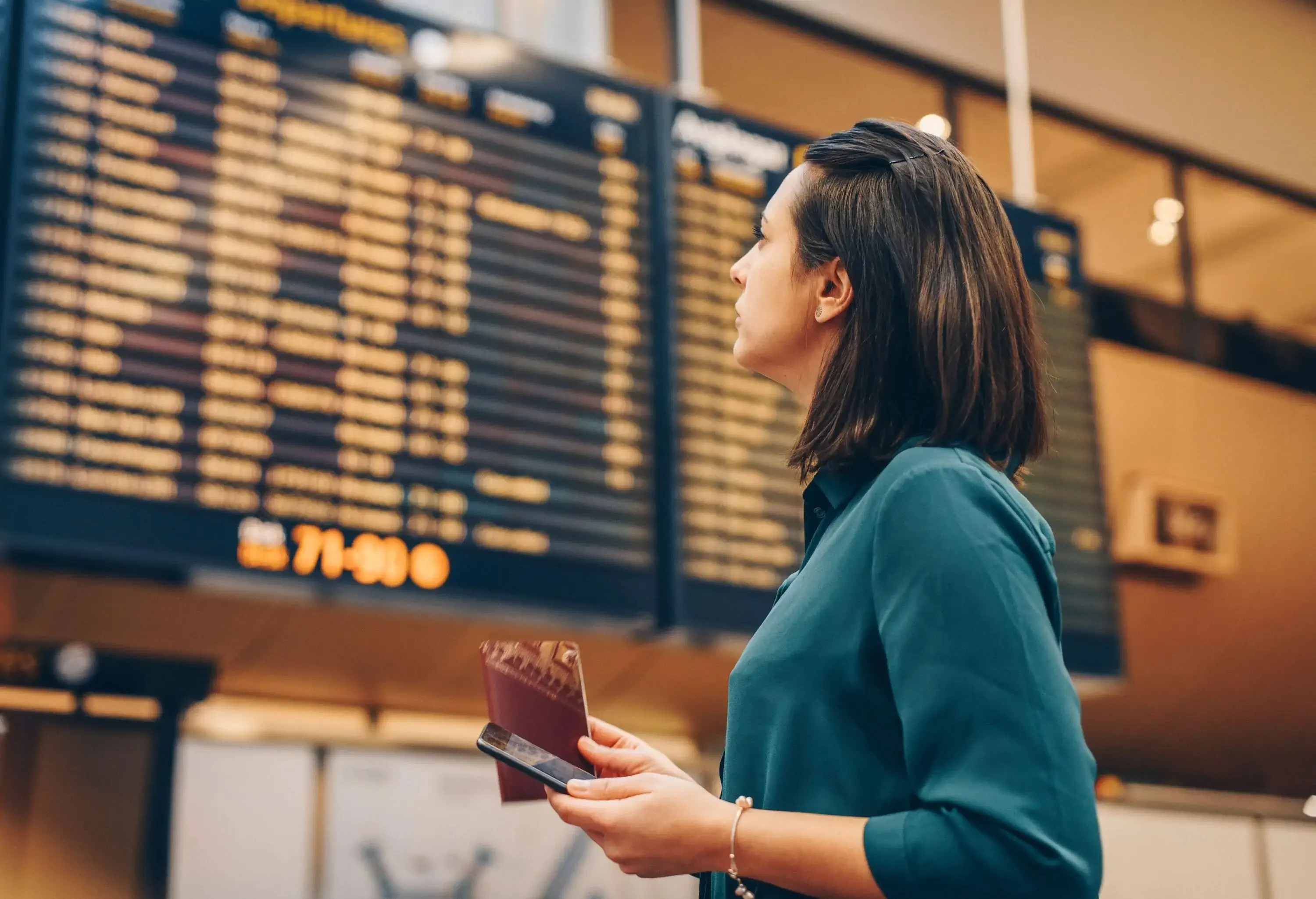 Side view of businesswoman looking at arrival departure board in airport