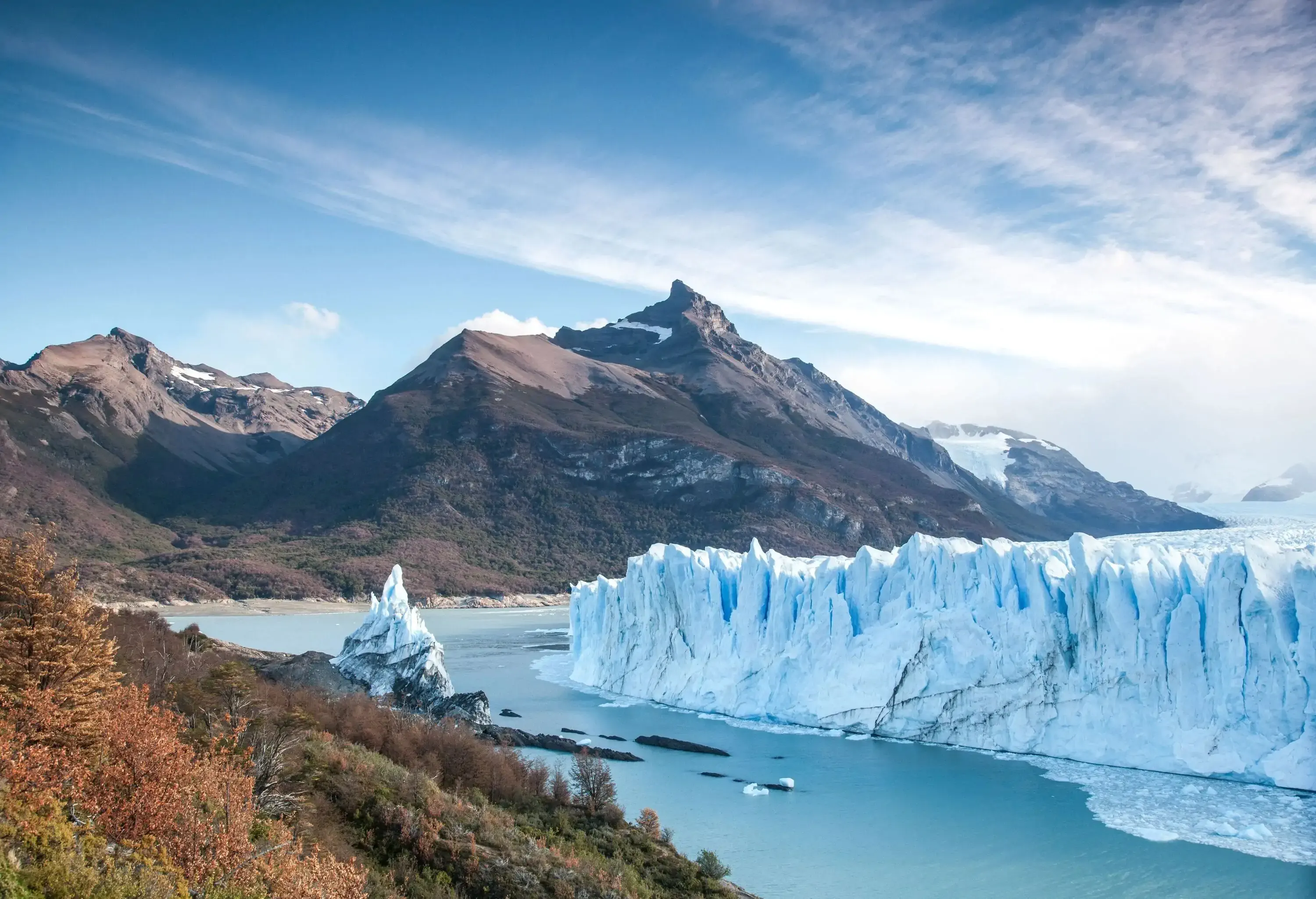 An iceberg standing amongst bare mountains