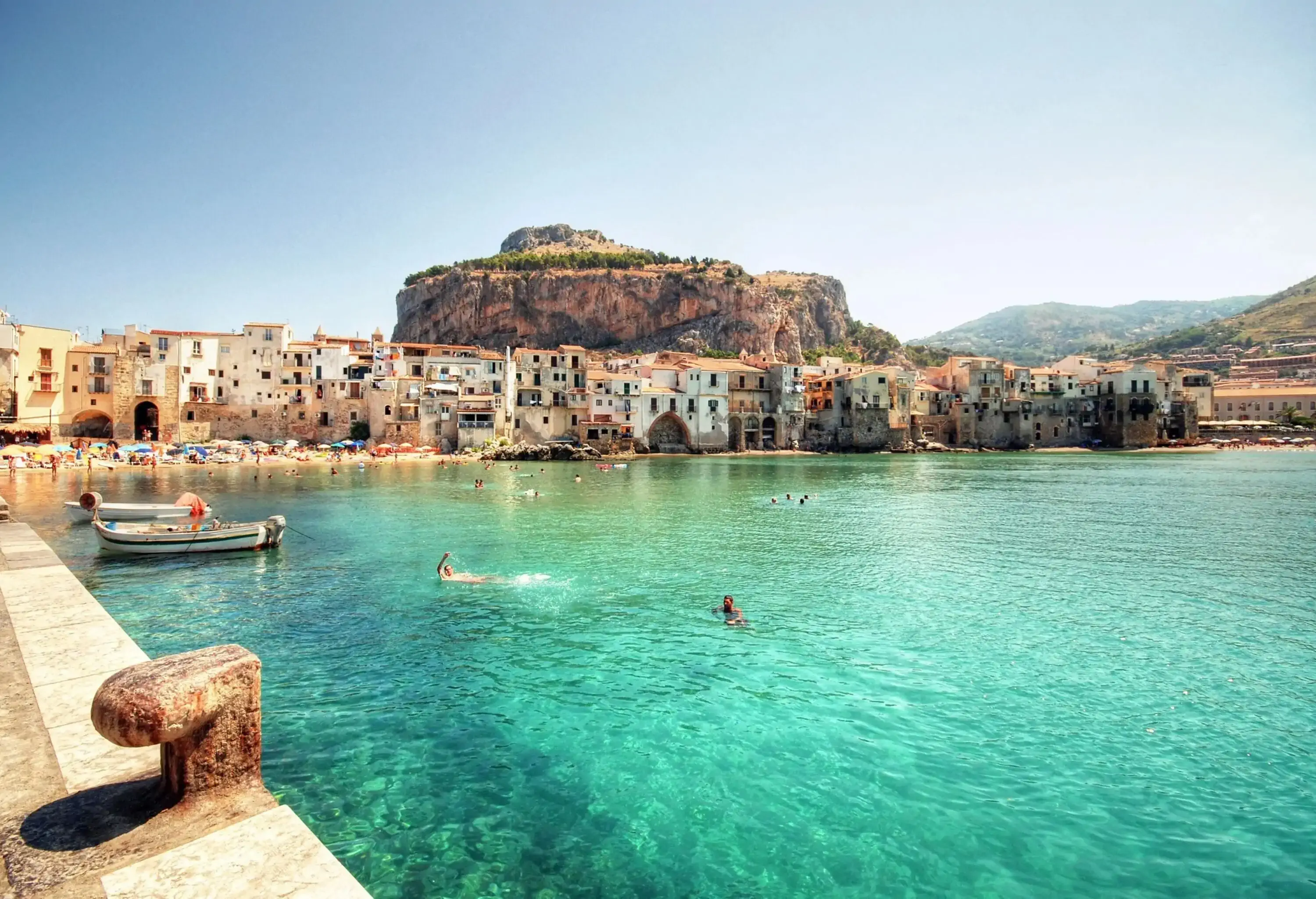 A village at the bottom of a mountain by a turquoise sea