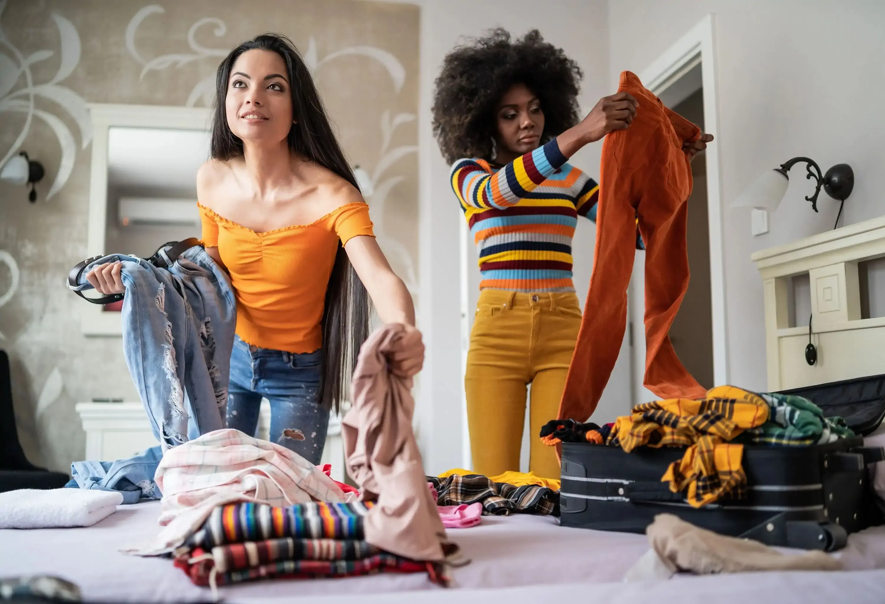 Girls busily organise their clothes, packing them neatly into a suitcase as they prepare for an upcoming adventure together.