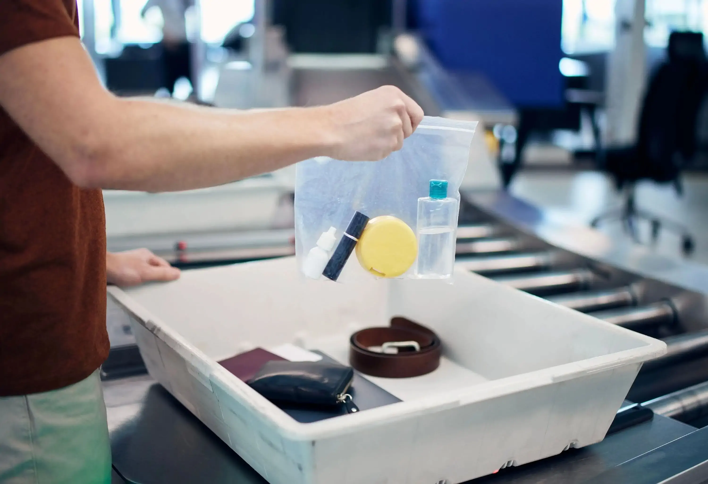 A man putting his liquids in a plastic bag into a bin at the security airport check