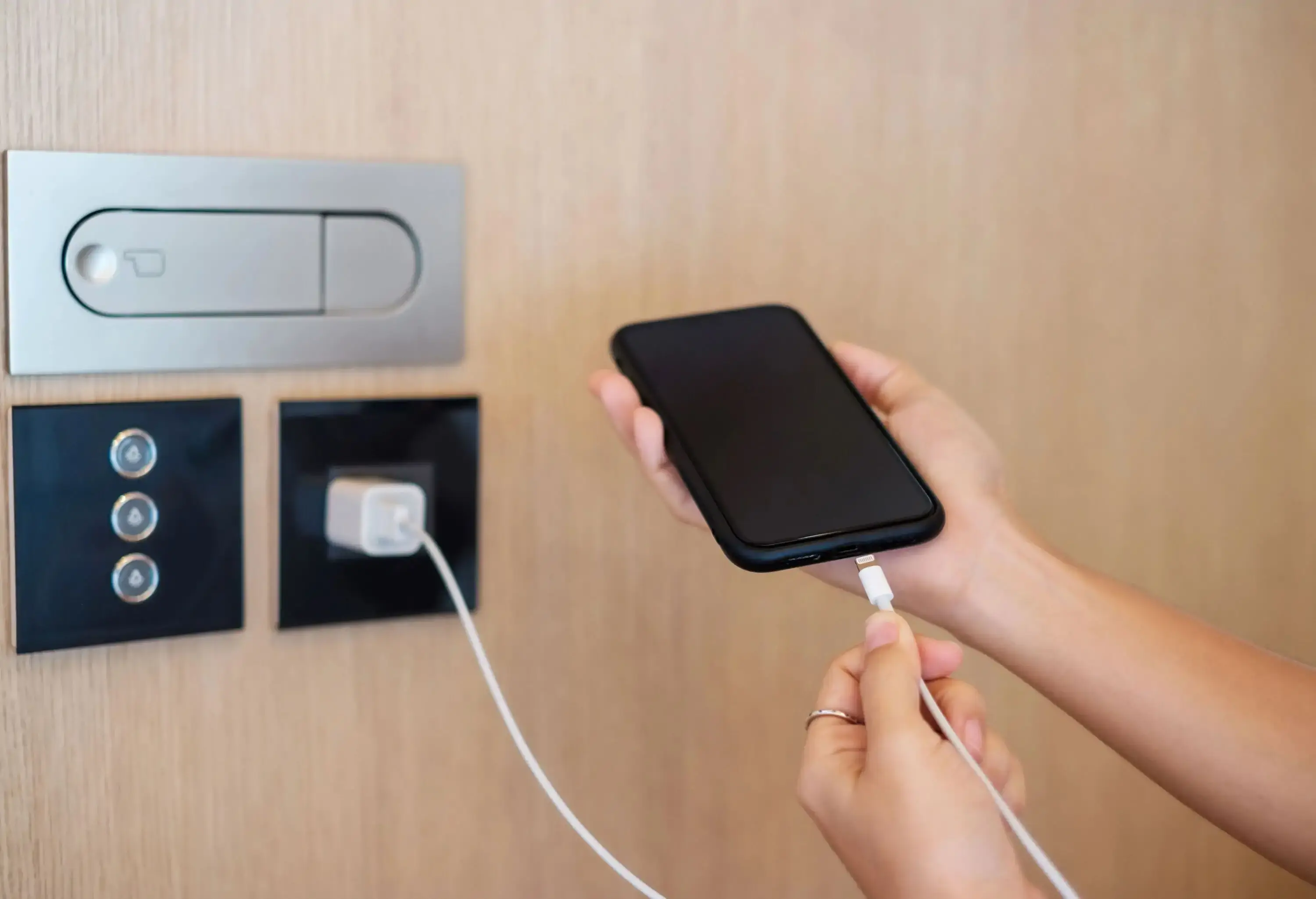 A hand charging a smartphone with a cable.