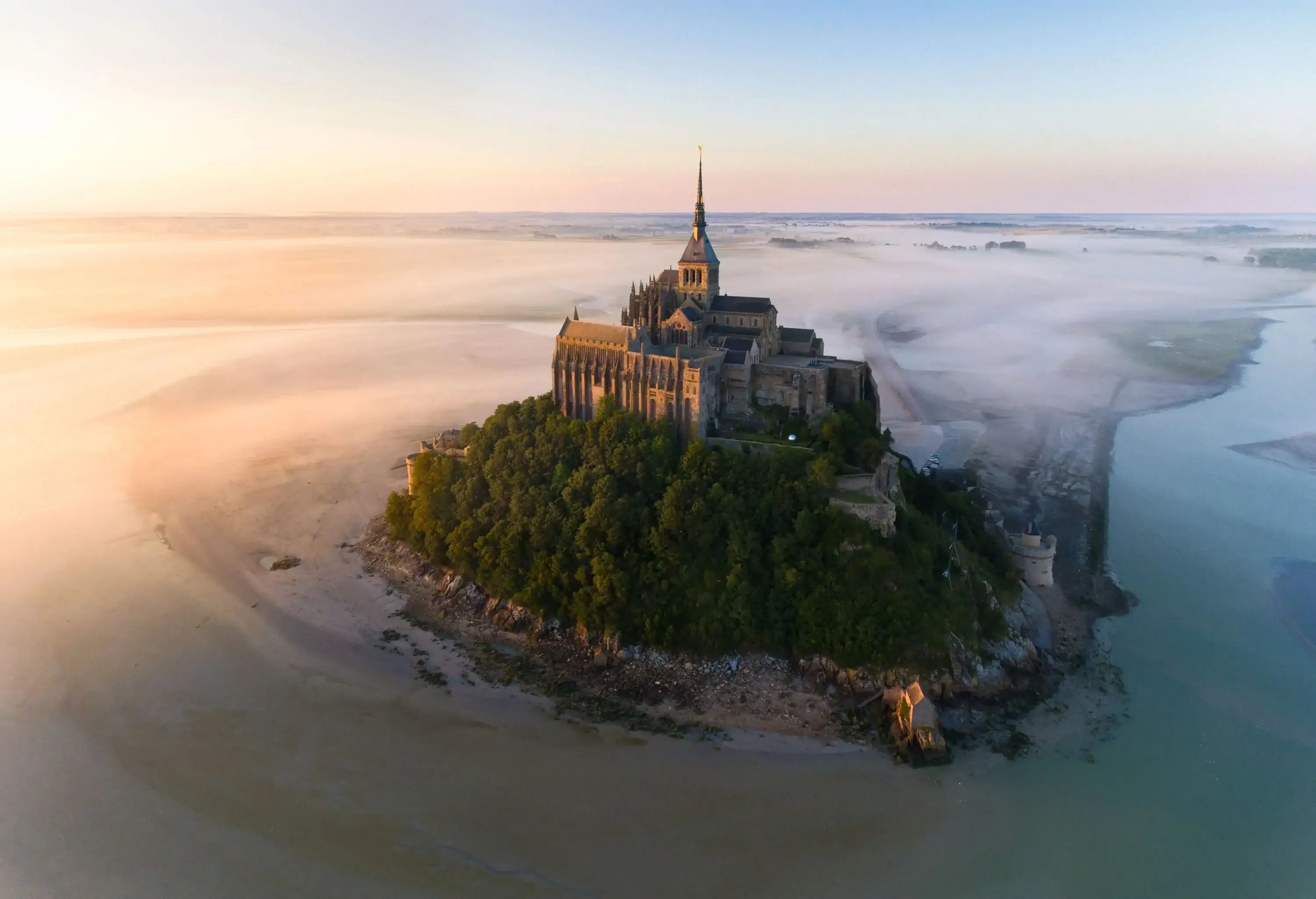 The abbey sat atop Mont Saint-Michel, surrounded by trees and water and shrouded in mist.