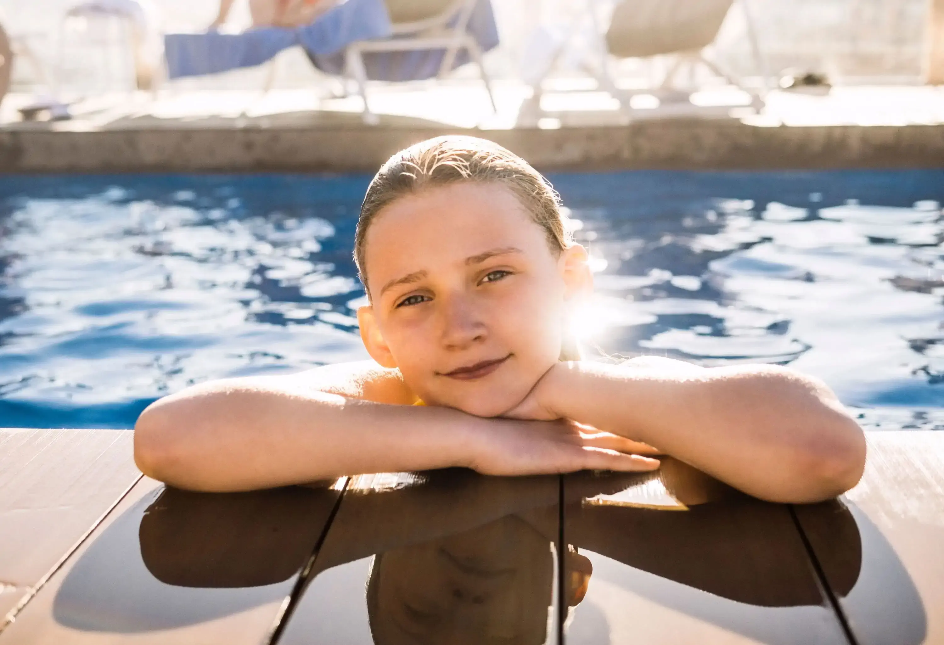 A little girl resting on the poolside.