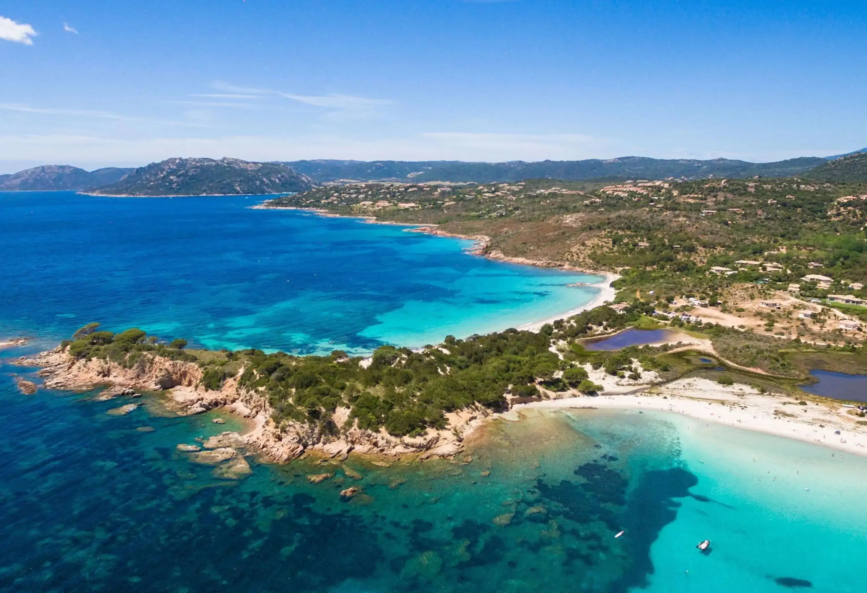 An island with wide bays and ocean pools surrounded by white beaches and rocky slopes.