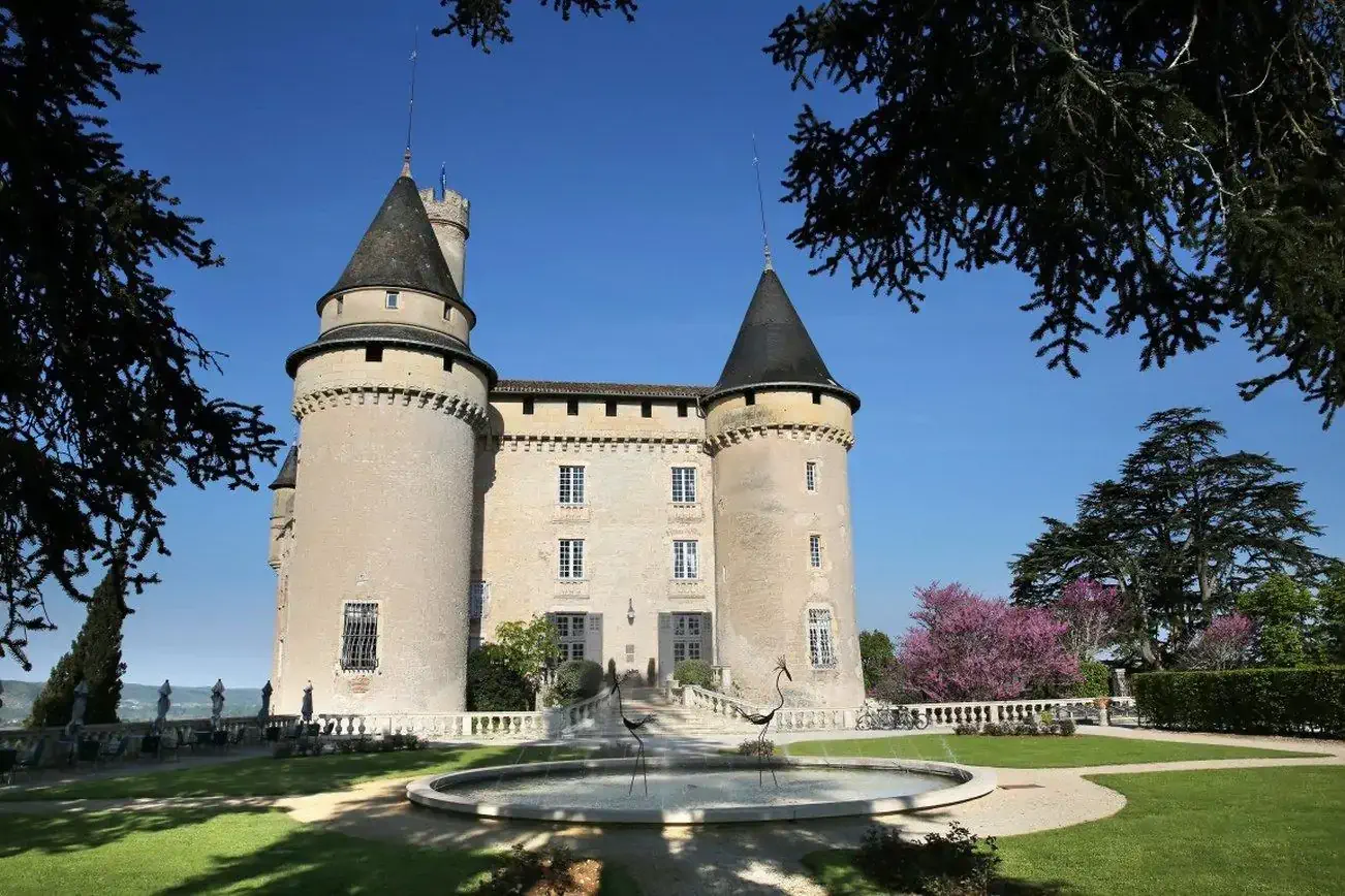 Facade of a medieval castle and its gardens with fountain pool