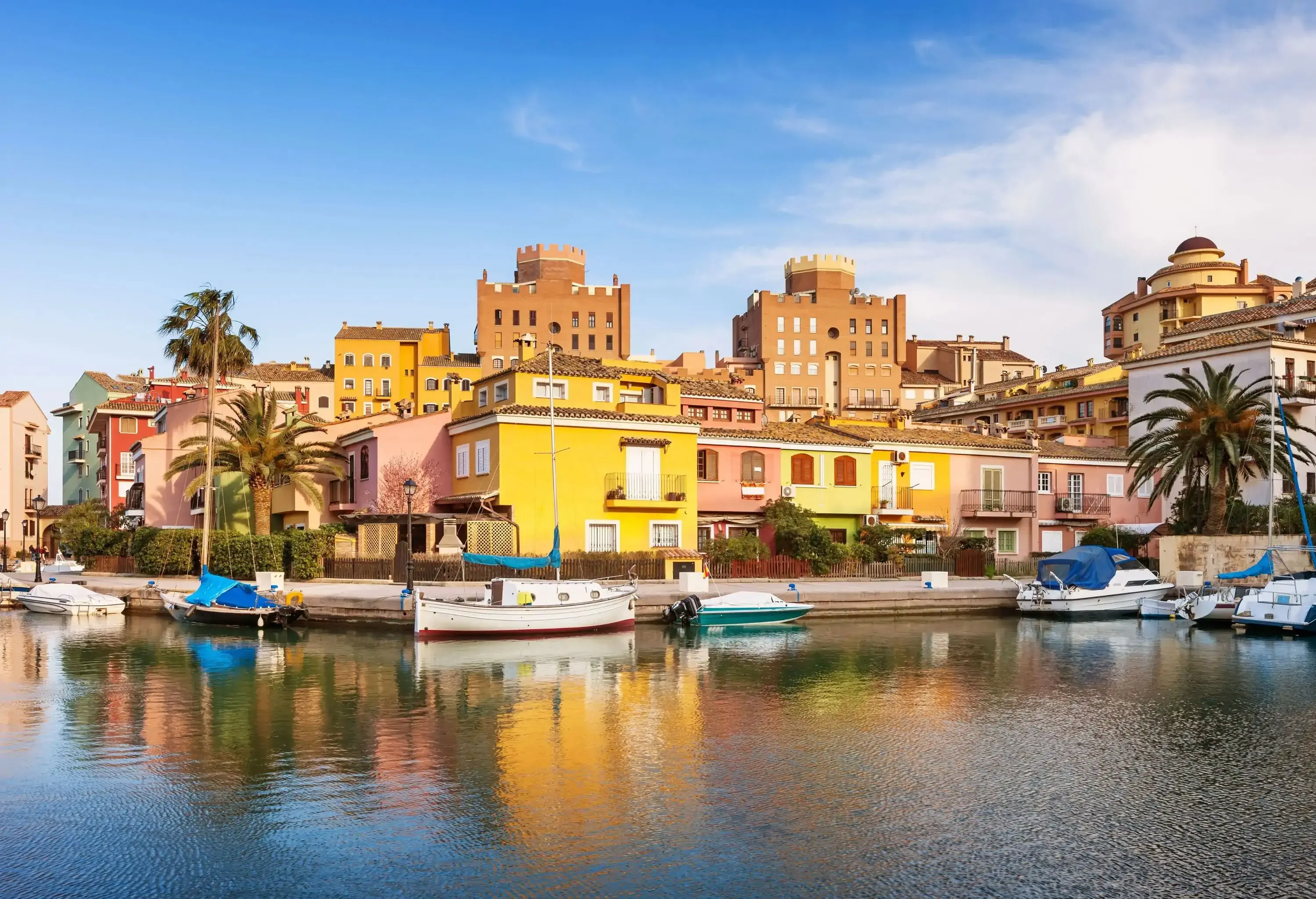 A small community of colourful houses alongside a port with tied boats.