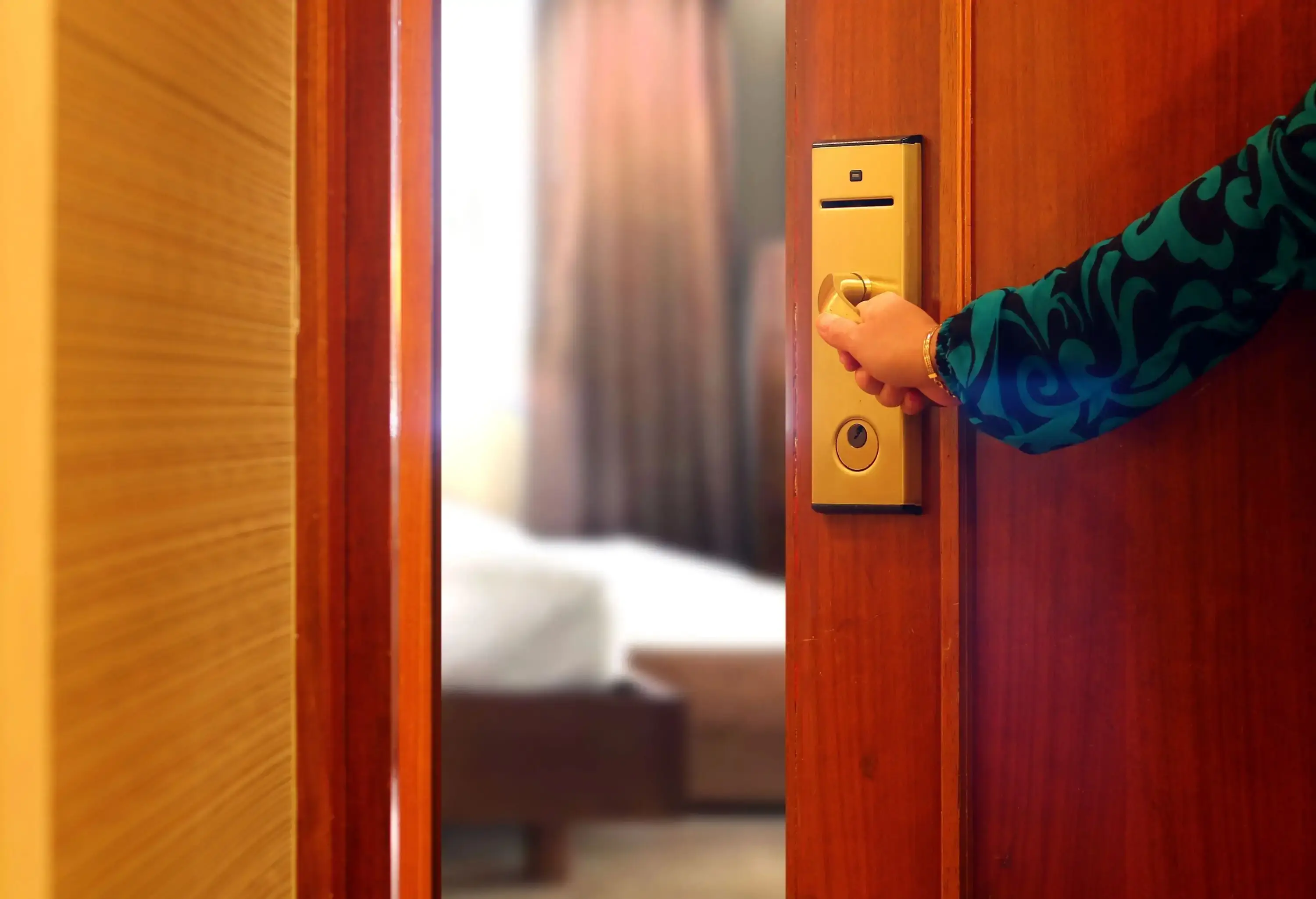 A woman's hand opening the door to a room.