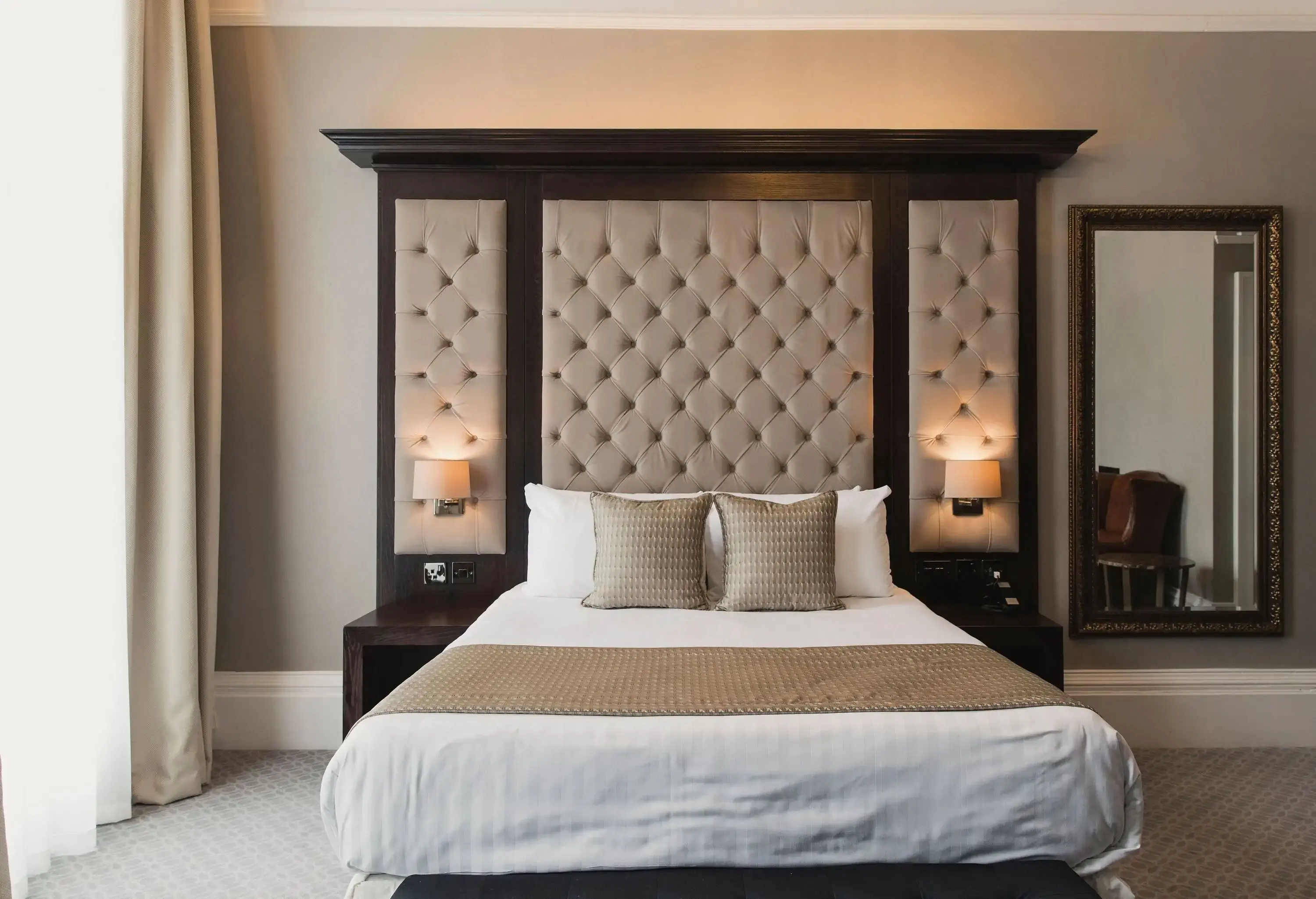 An elegant room with a cosy double bed and tufted cream headboard.