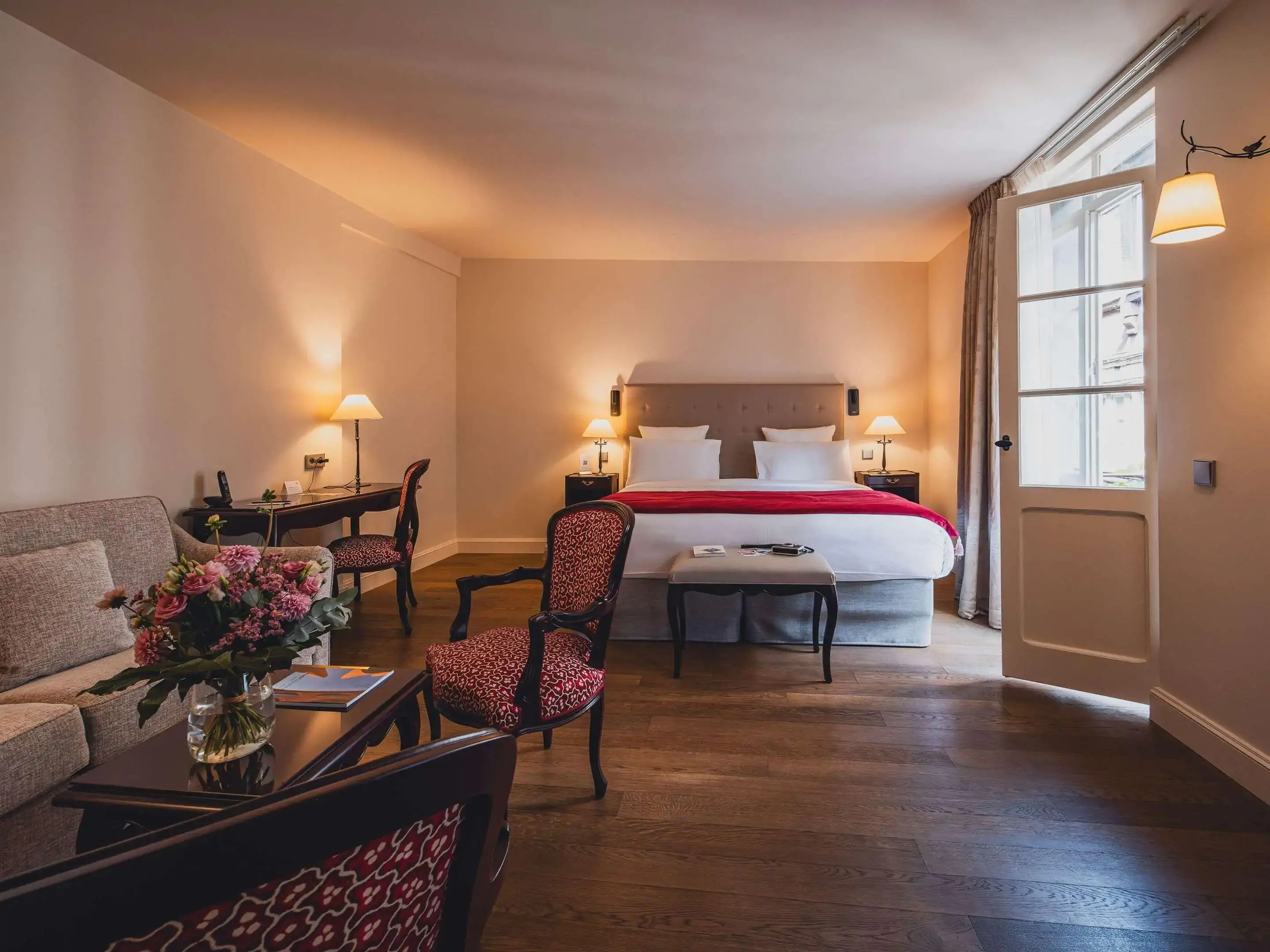 A simple elegant hotel room with wooden floor, a bed and a lounge area