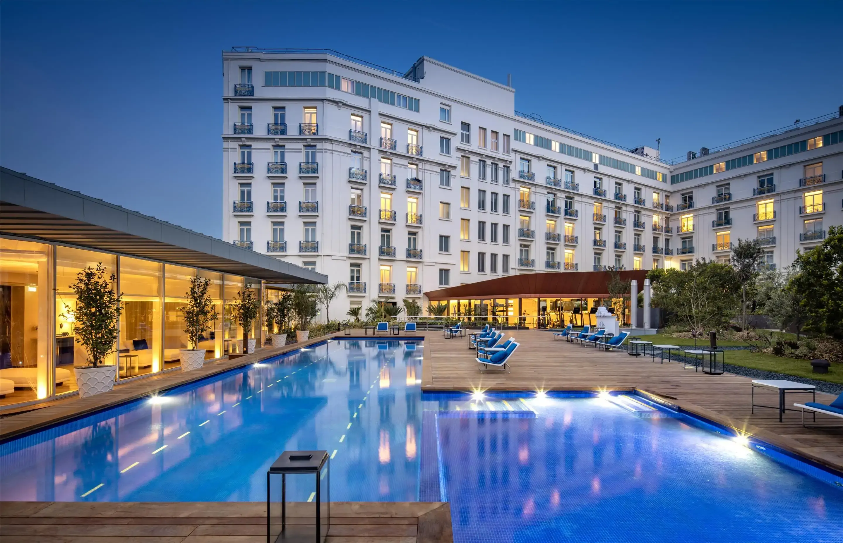 Exterior of a large luxury hotel with swimming pool at dusk