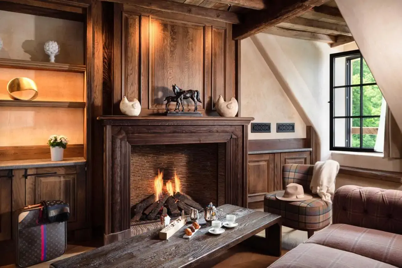 A rustic hotel lounge with wooden furniture, plaid prints and a roaring fireplace
