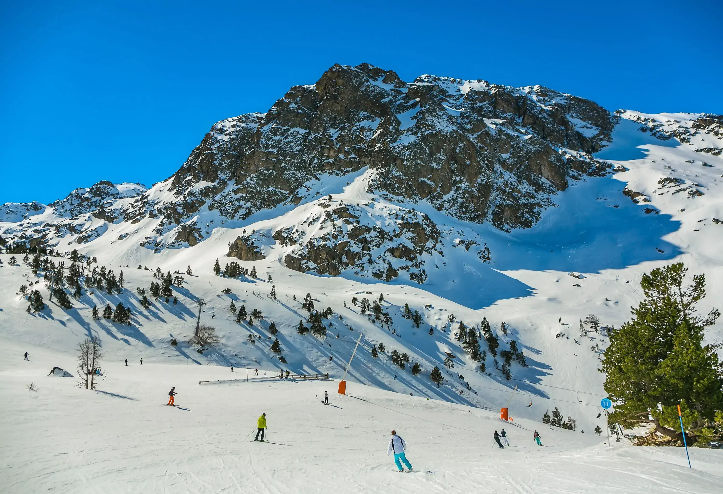 Hills blanketed in snow where skiers can be seen sliding down the slopes.