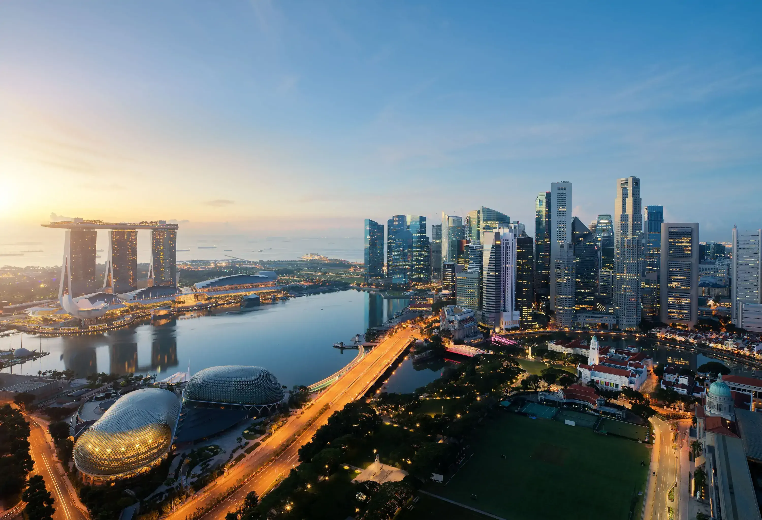 A cluster of modern skyscrapers along a busy highway and a bay surrounded by futuristic structures with unique architecture.