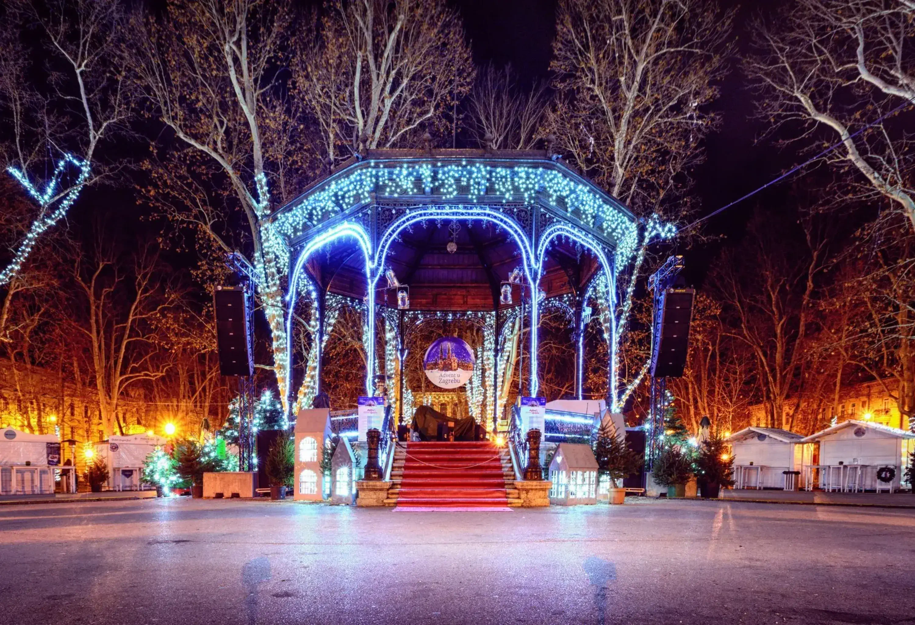 The polygon covered stage is lit with bright LED lights and surrounded by tall bare trees.