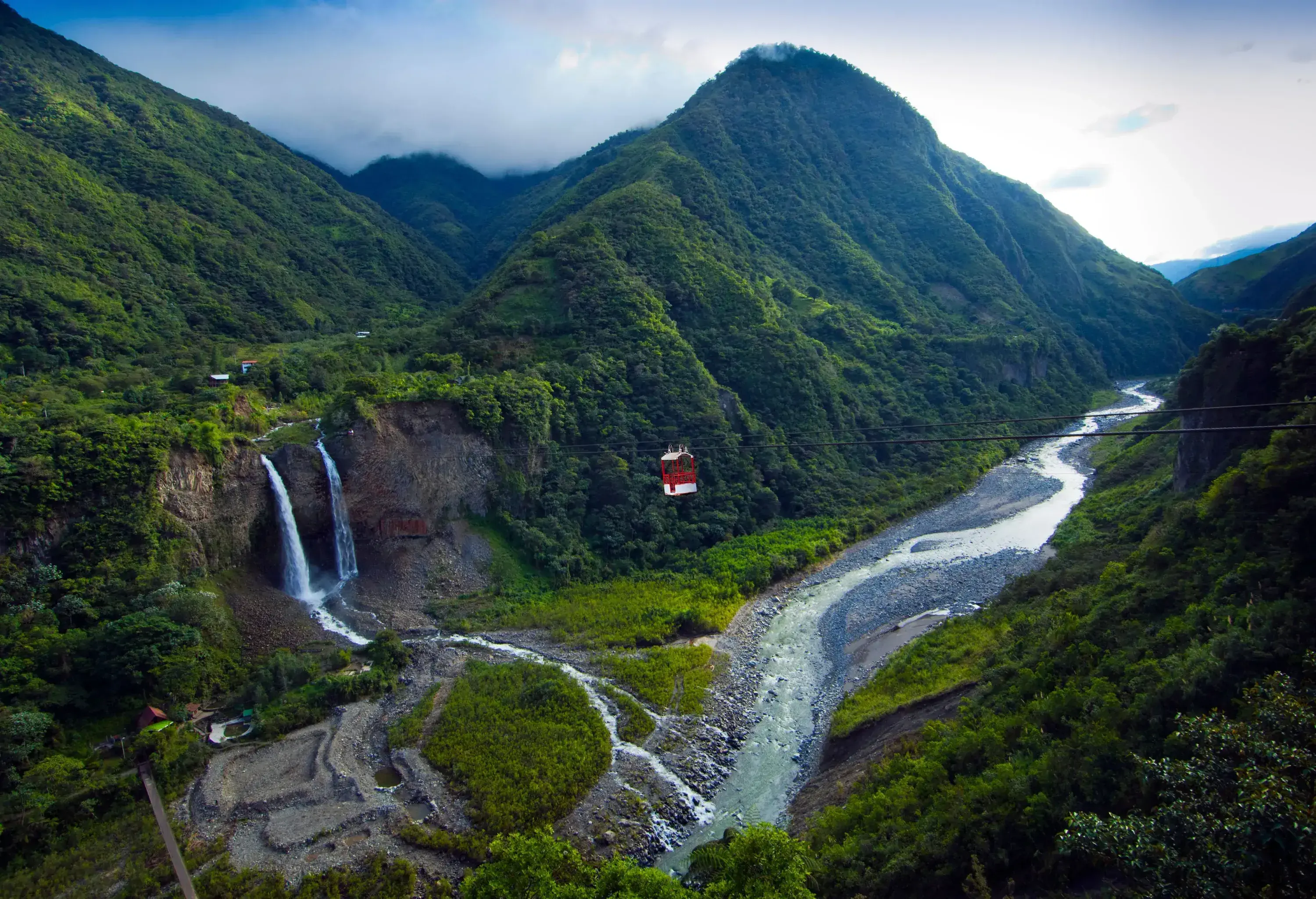 A pair of waterfalls pouring into a shallow river that meanders across a narrow valley.