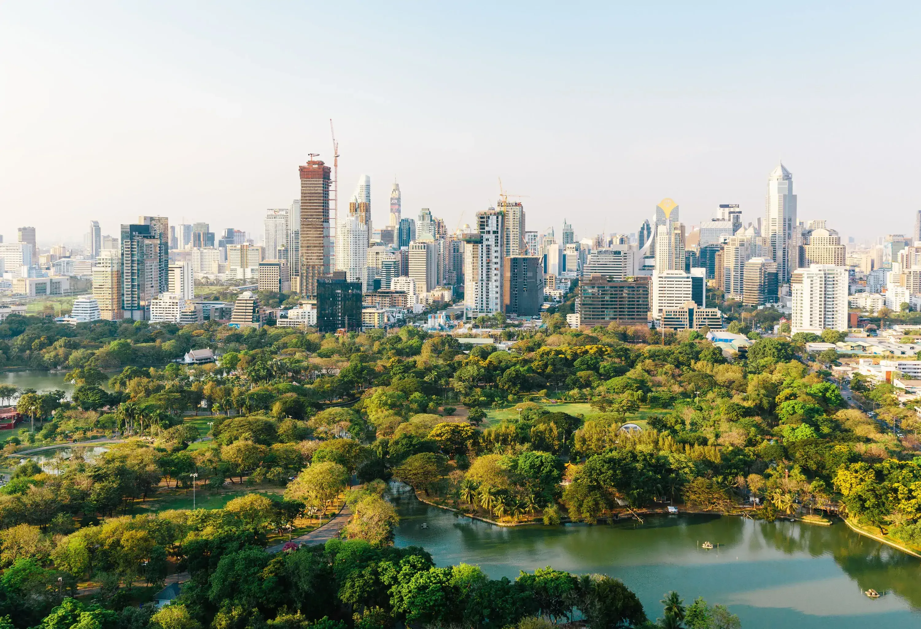 A wide park area with a lake and high-rise buildings in the distance.
