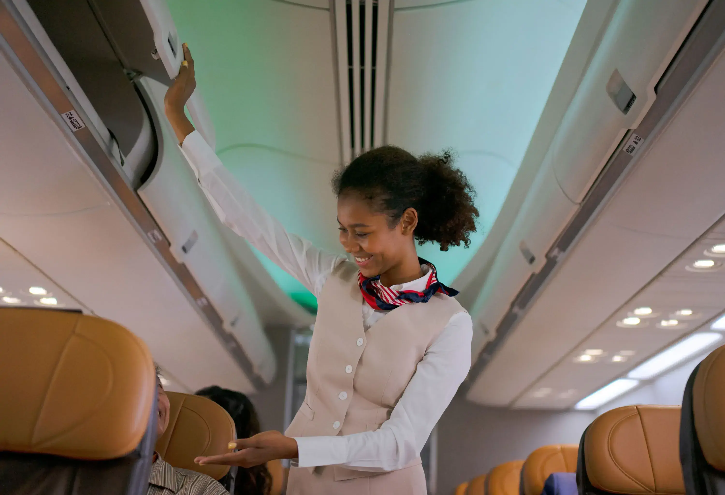 Flight attendant smiling and closing overhead lockers before take-off