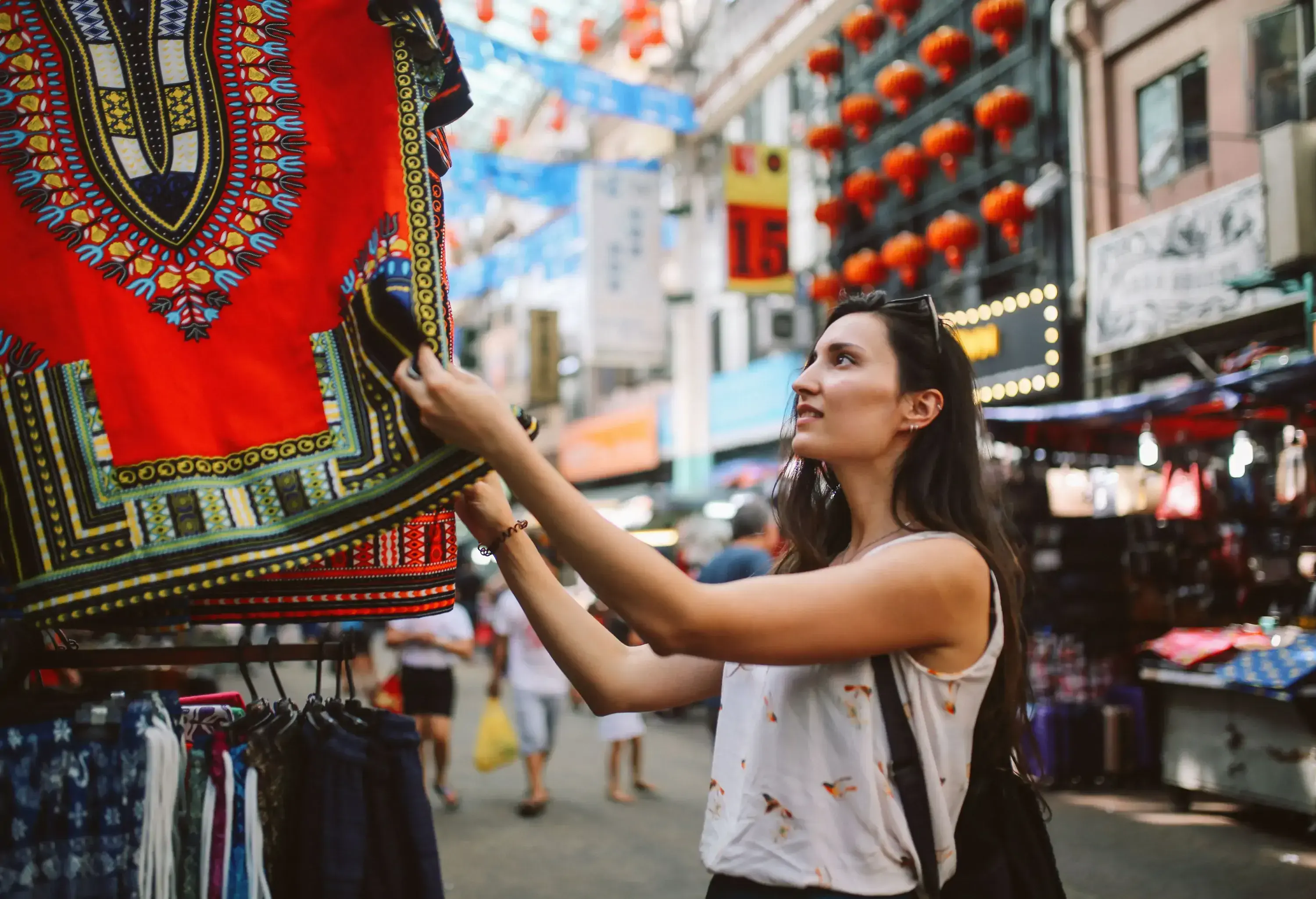 A lady tourist checks on the multicoloured garments hung on a stall in the market.