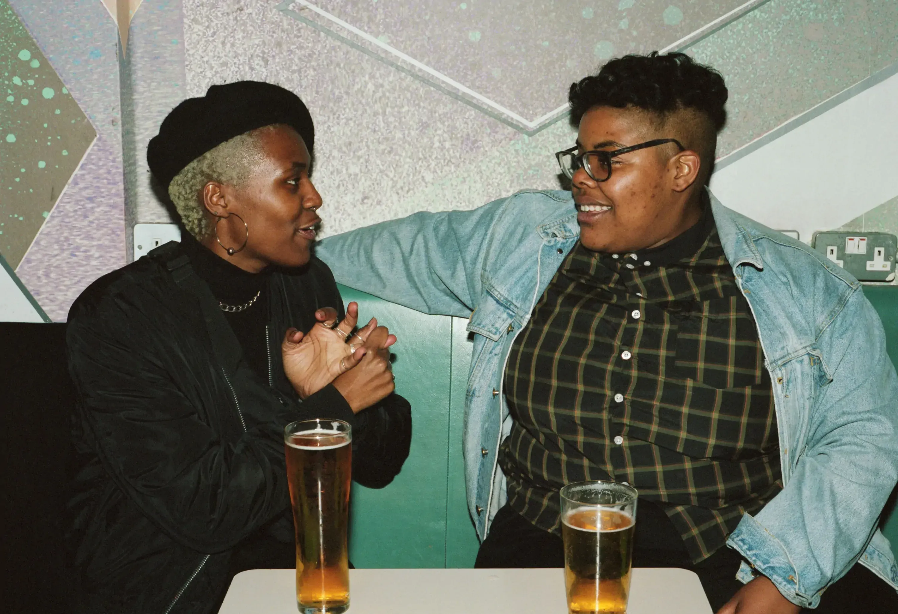 Two friends telling stories in a bar over a glass of beer.