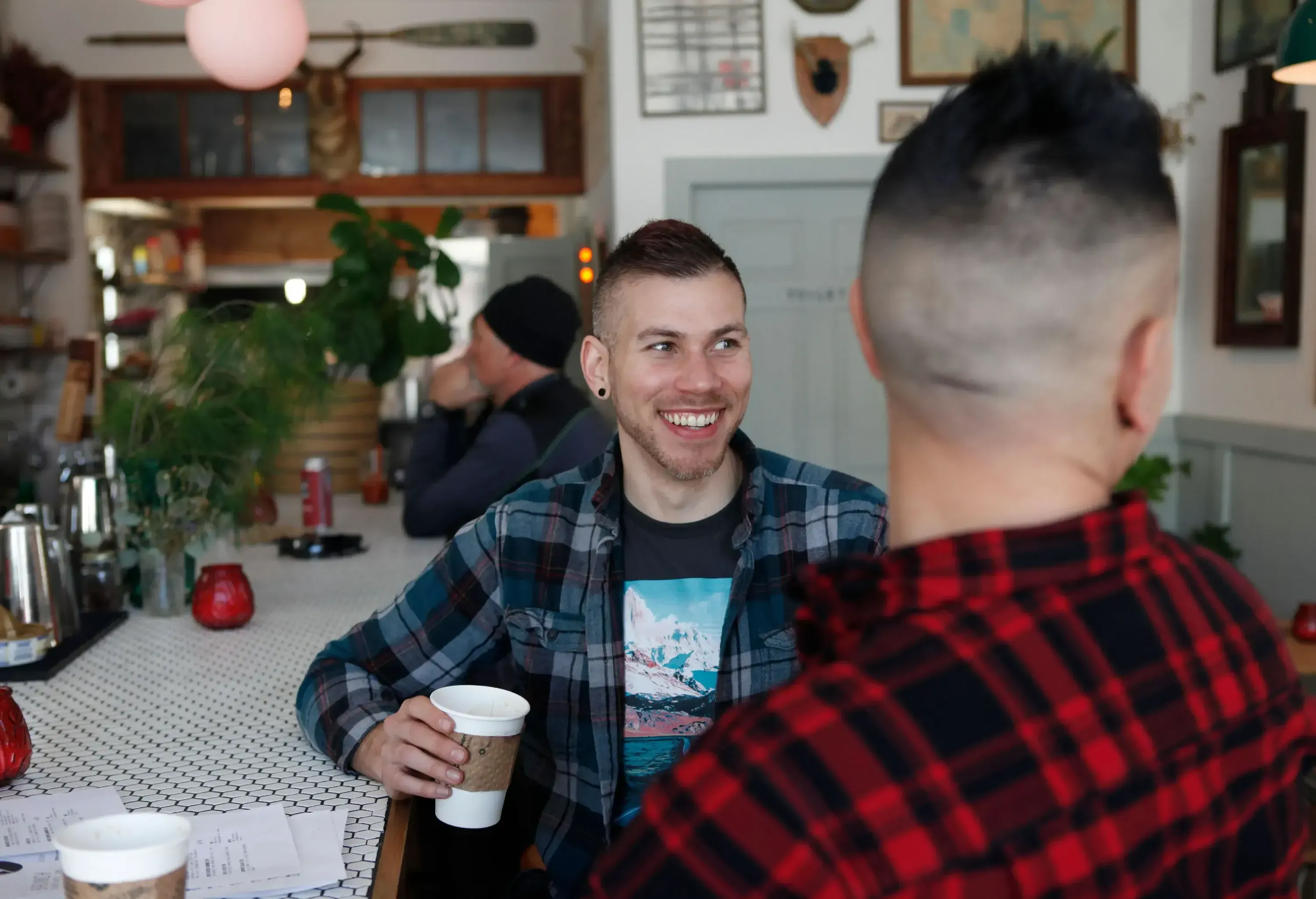 Two men sitting at the bar of a café, having conversations over coffee.