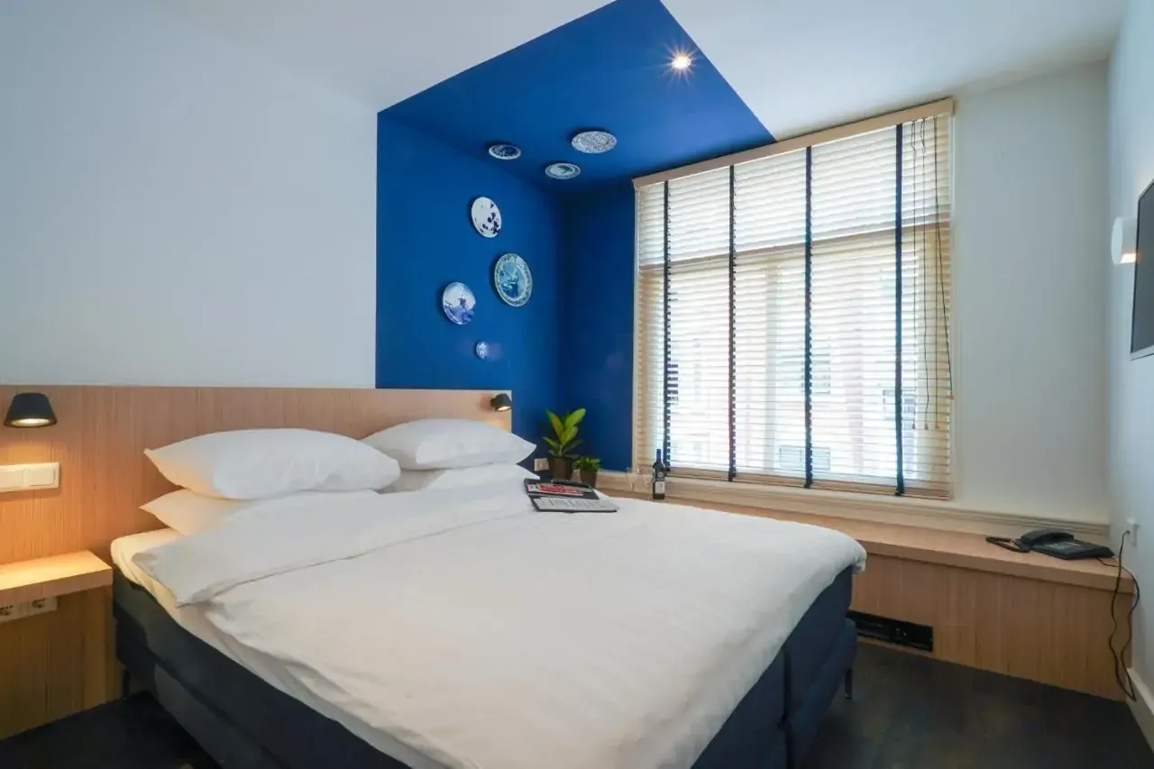 Hotel room with one wall part painted in blue and hanging decorative plates in Dutch porcelain