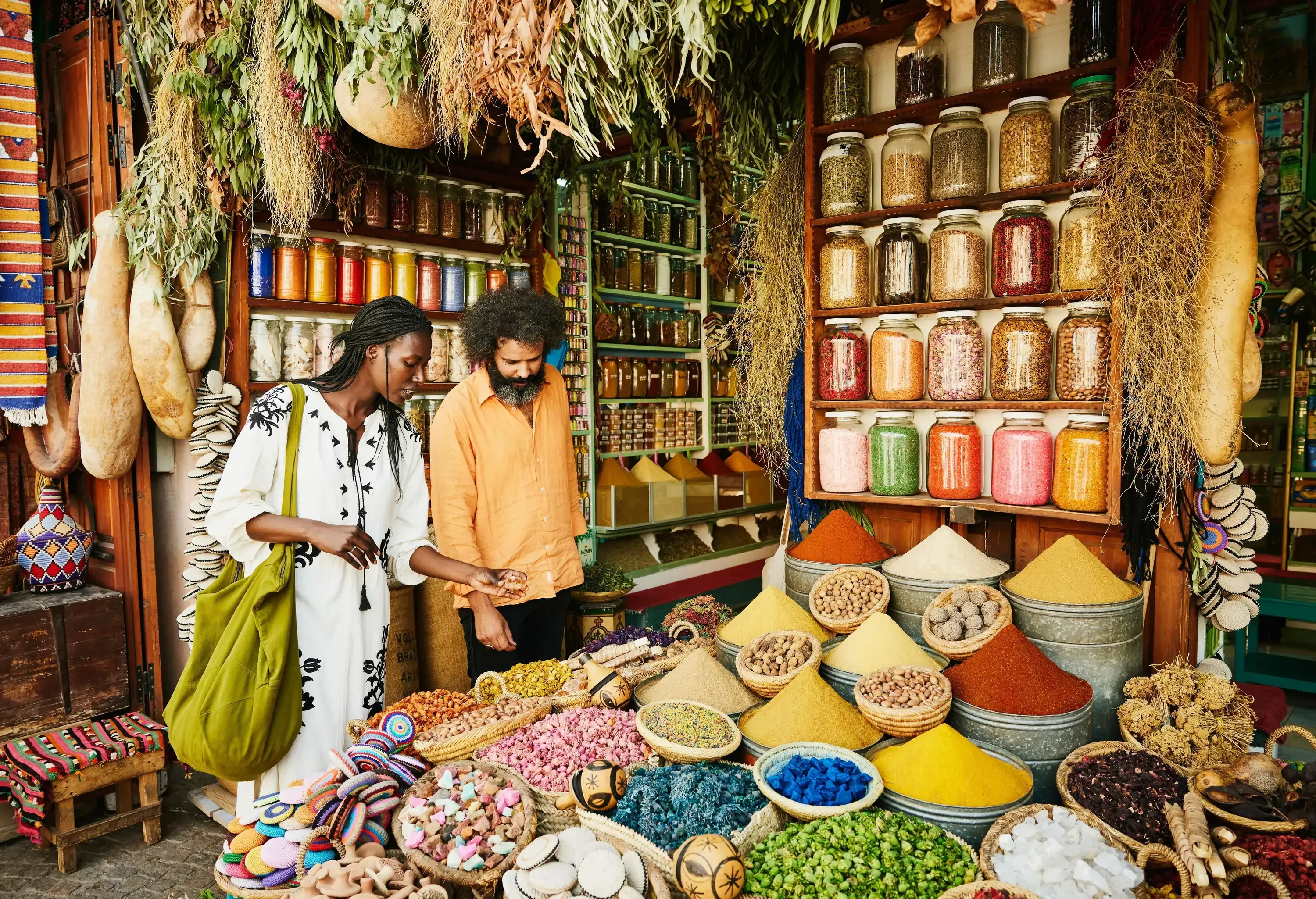A couple looking down at the selection of dried goods in a vibrant spice shop.