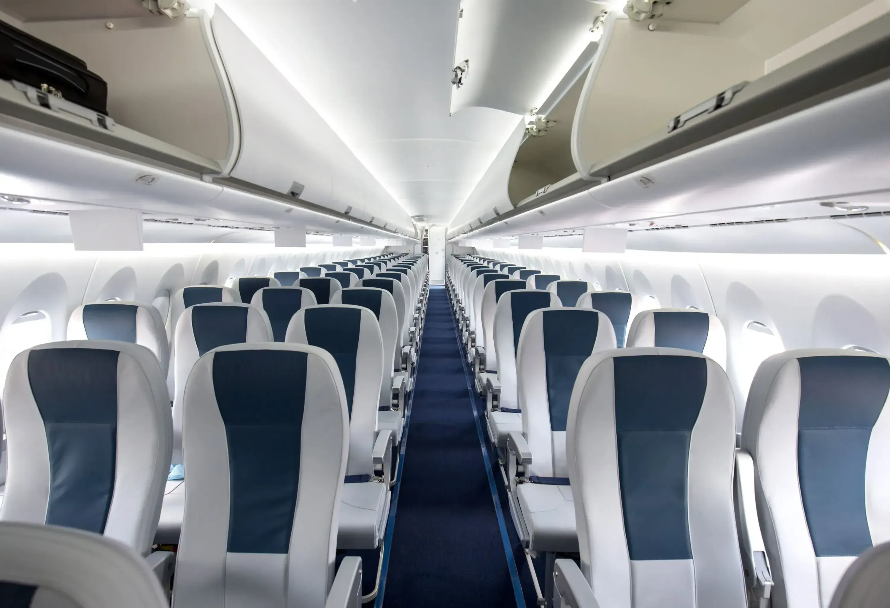 An empty airline cabin with a carpeted aisle. 