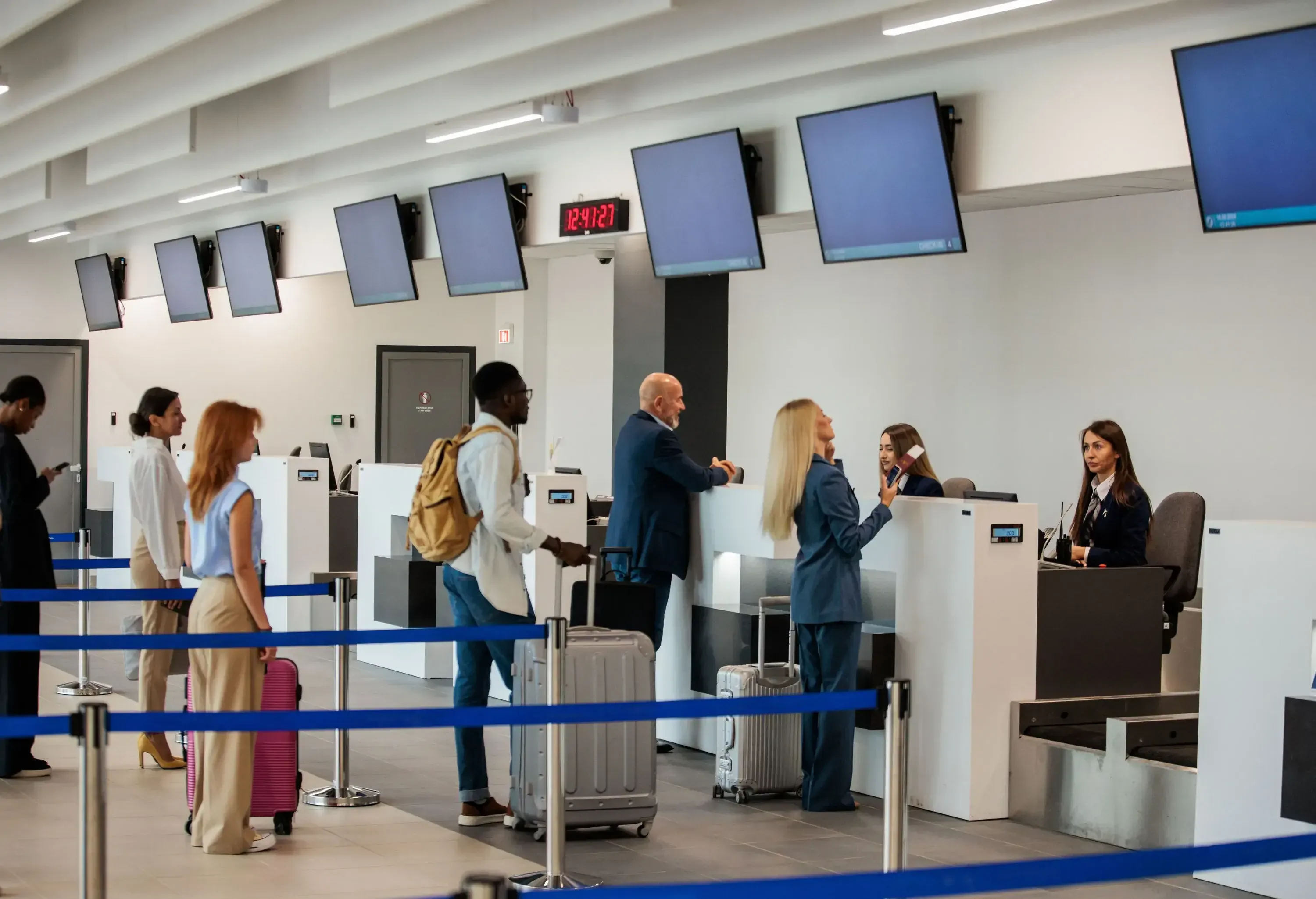 People at the airport queuing at the check-in desk for information about their flight.
