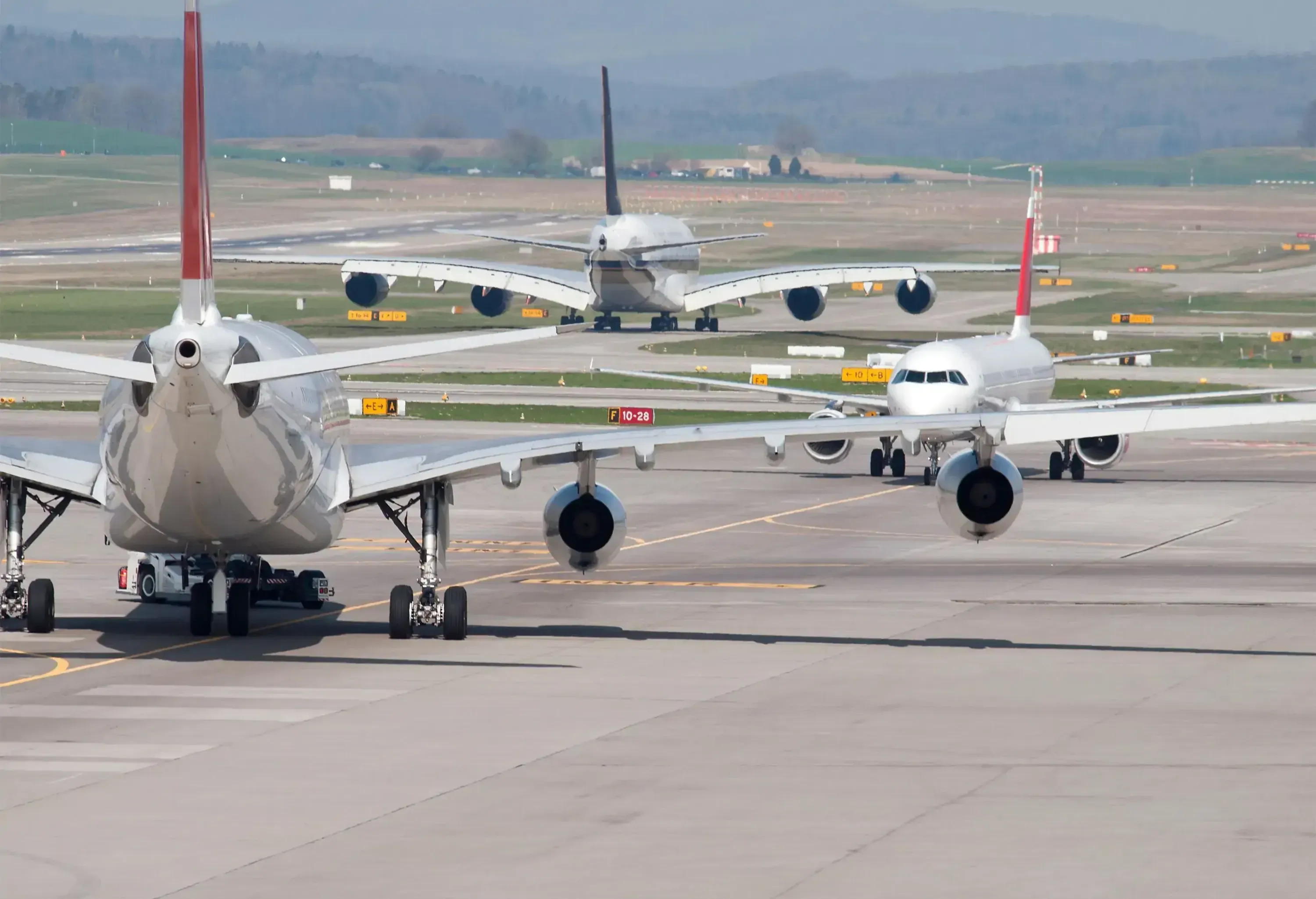 Three passenger aircrafts in heavy traffic on the taxiway of Zurich international airport. Aircraft types on picture include  Airbus A380 (middle). Two moving away, one approaching. Looks like the aircrafts are deadlocked in a taxiway traffic jam.
